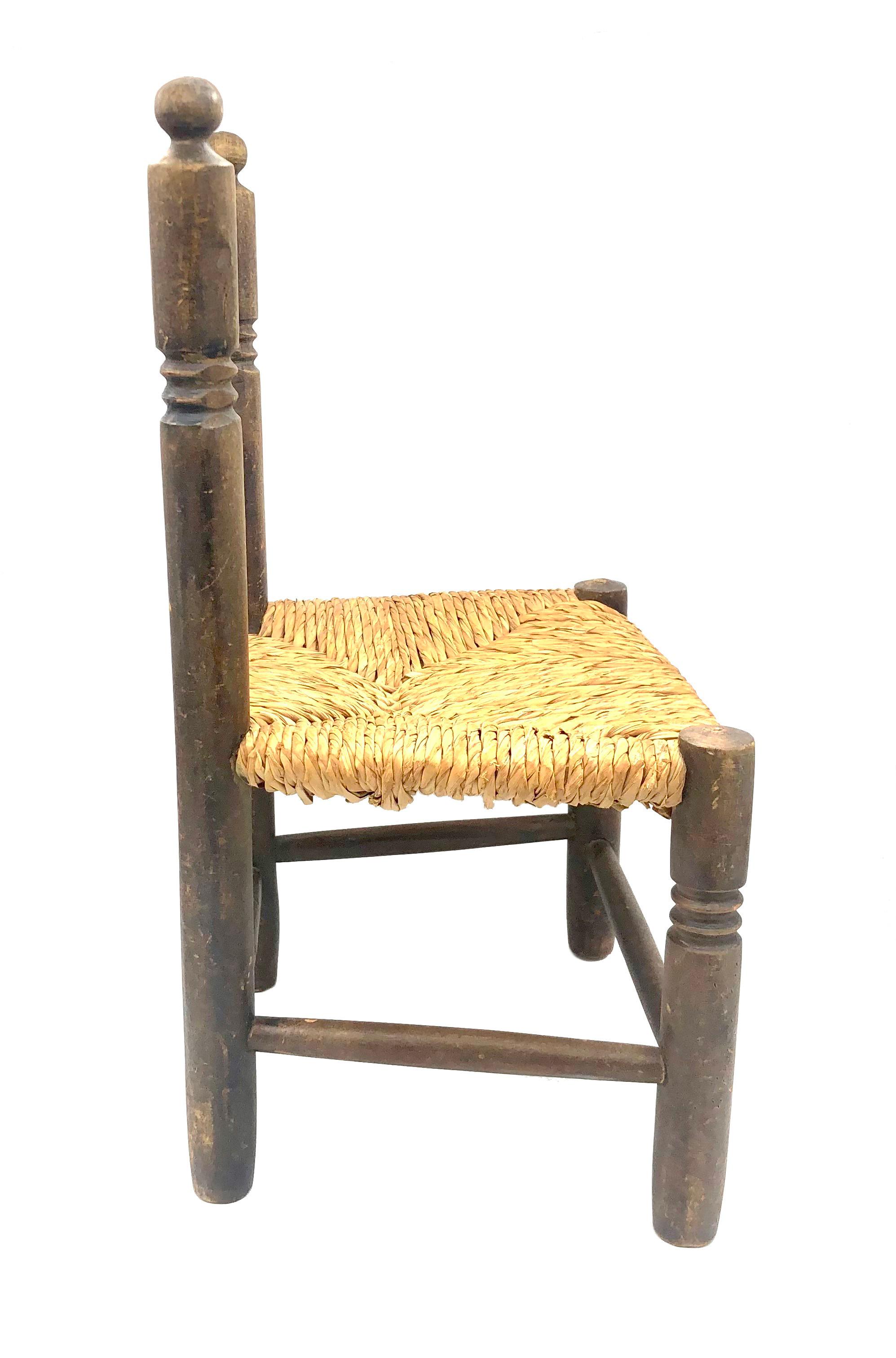 Cette solide chaise d'enfant a été fabriquée en chêne tourné dans le dernier quart du 19e siècle. L'assise en osier suit un motif géométrique et est en bon état. Les pieds et le dos du cair sont décorés de motifs géométriques. 
découper des cercles.
