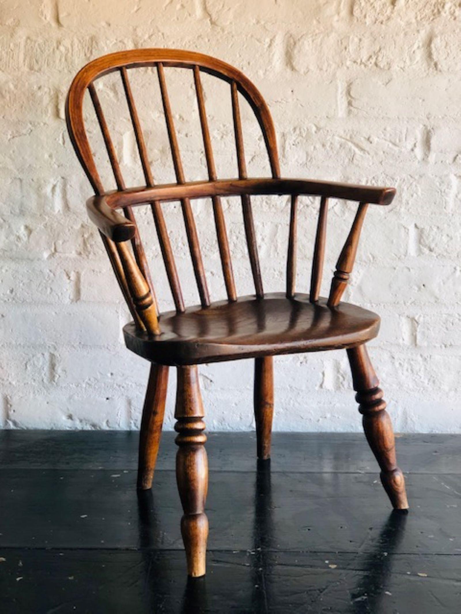 Ancien fauteuil Windsor d'enfant du 19e siècle, anglais 

Magnifique chaise Windsor d'enfant en frêne et orme.  Dos en forme d'arceau et de bâton, bras avec supports tournés.  Le siège repose sur quatre gros pieds tournés et une assise en chêne