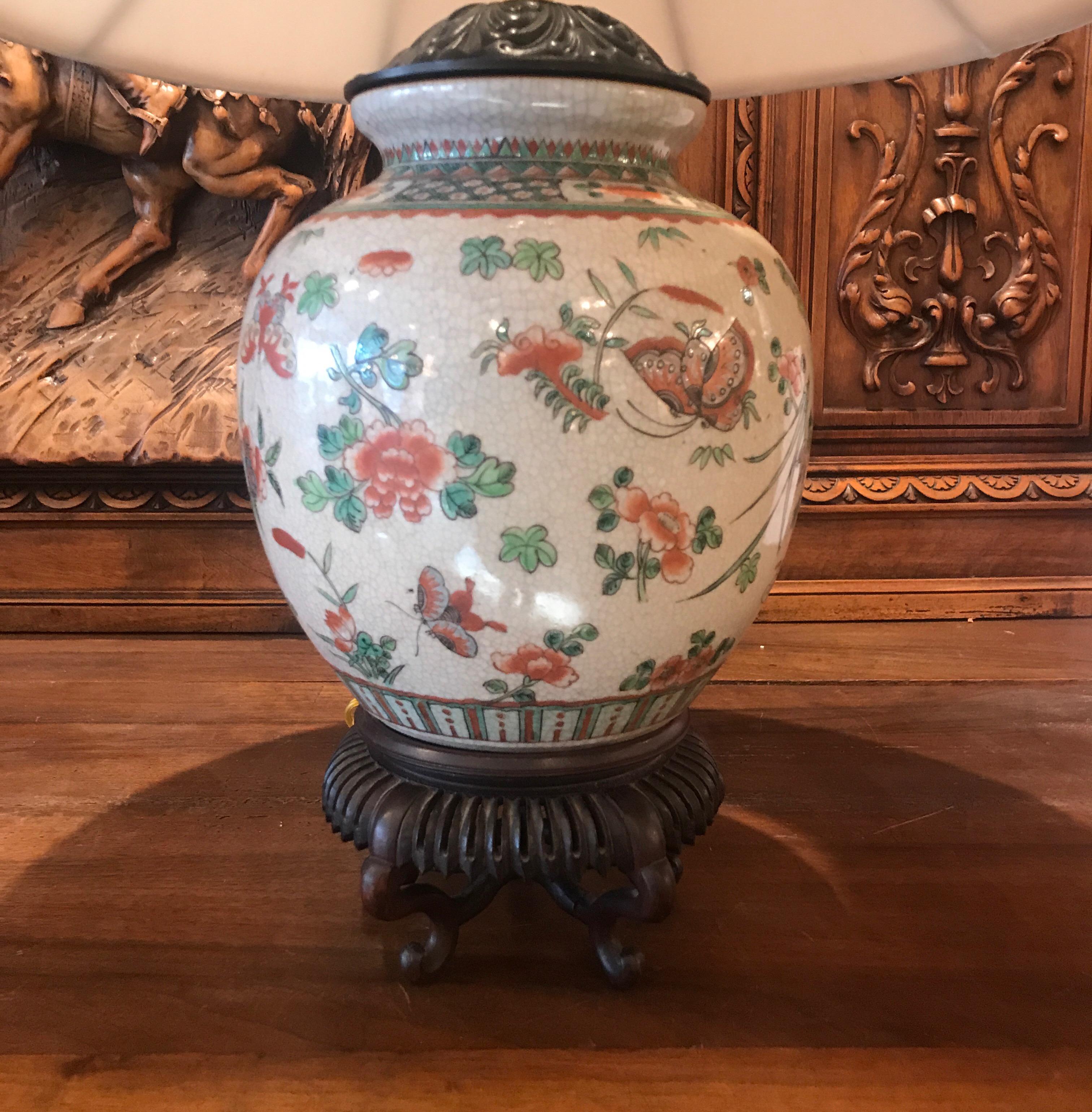 A late 19th century hand painted porcelain vase with hand carved rosewood base now as a lamp. This vase was lamped in the first quarter of the 20th century with hand painted floral decoration with a slight crackles glaze. The base is a beautifully