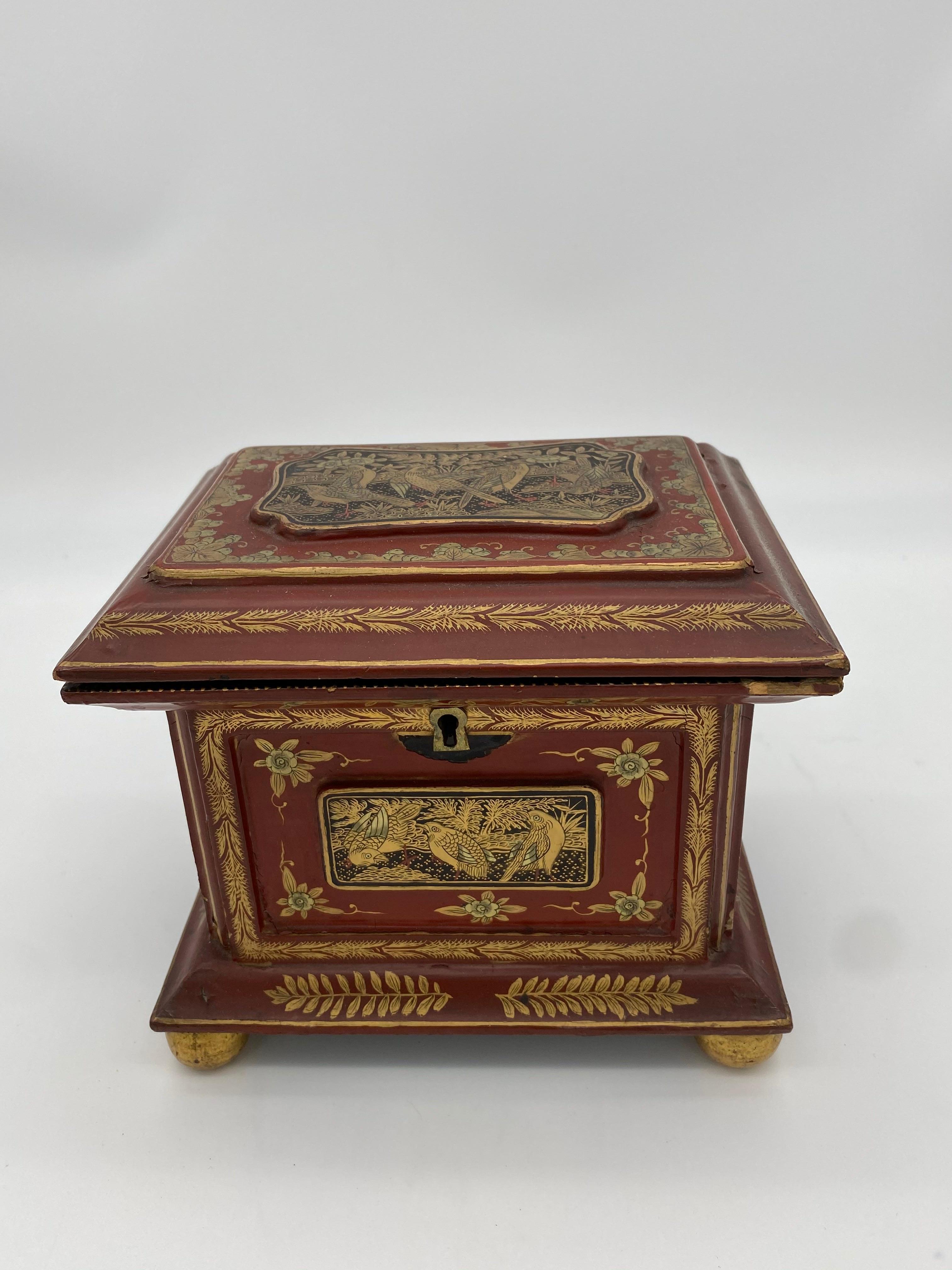 Antique 19th century Chinese red and black lacquered box with gold accents. Lid and sides feature hand painted scenes of flowers, leaves, and birds. Lid opens to reveal a small lacquered tray which can be removed to access the compartment below. Box