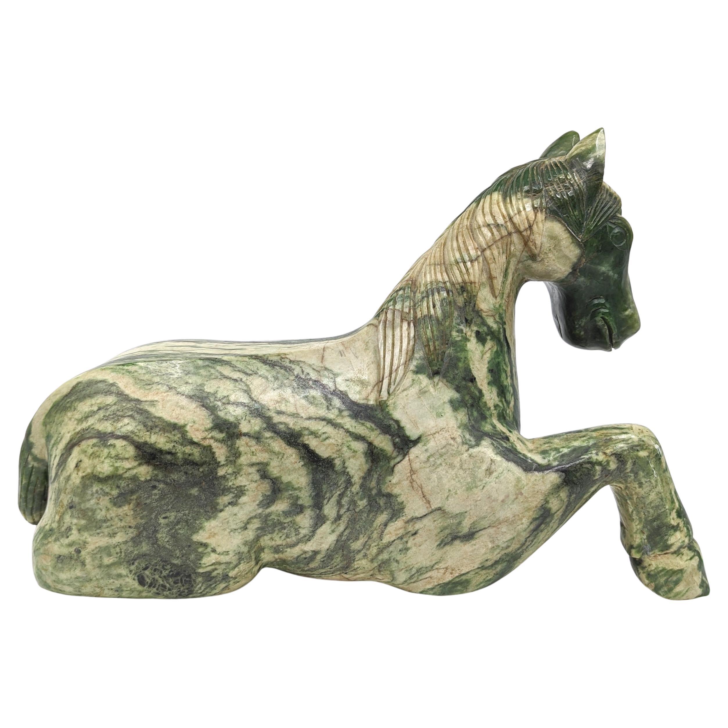 A monumental size (14kg) Chinese recumbent Tang Horse, circa mid to late 20th Century, possibly older. The sculpture is executed in Spinach Jade, a material highly prized for its deep green hue and symbolic significance. The horse is depicted in a