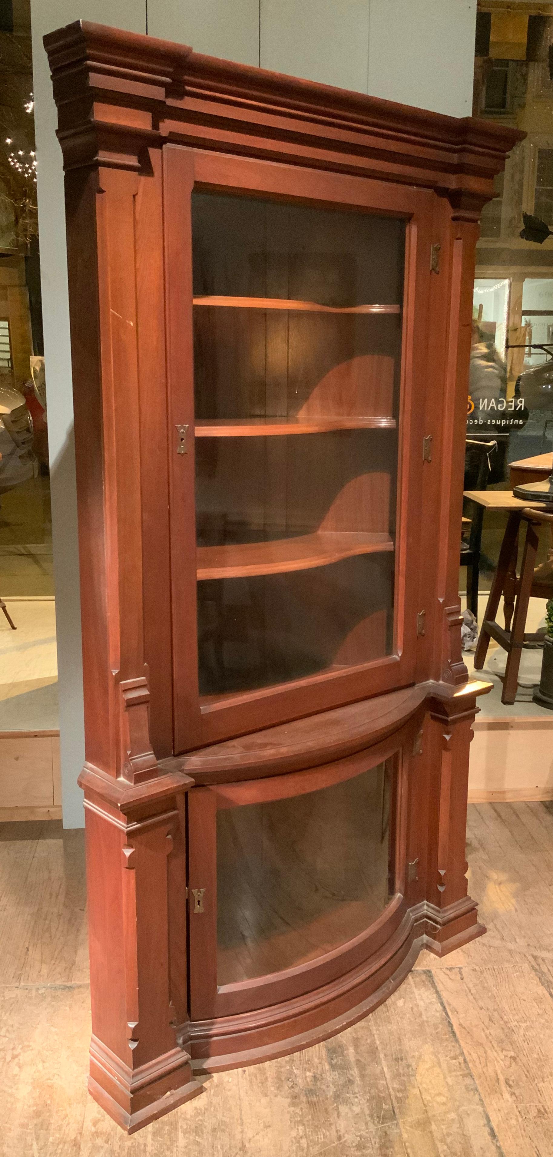 a very nice and beautifully detailed late 19th Century corner Cabinet, with a lower case with curved glass door. the cabinet has sculpted shelves in the upper portion, and stepped capitals. from an upper hudson valley home.