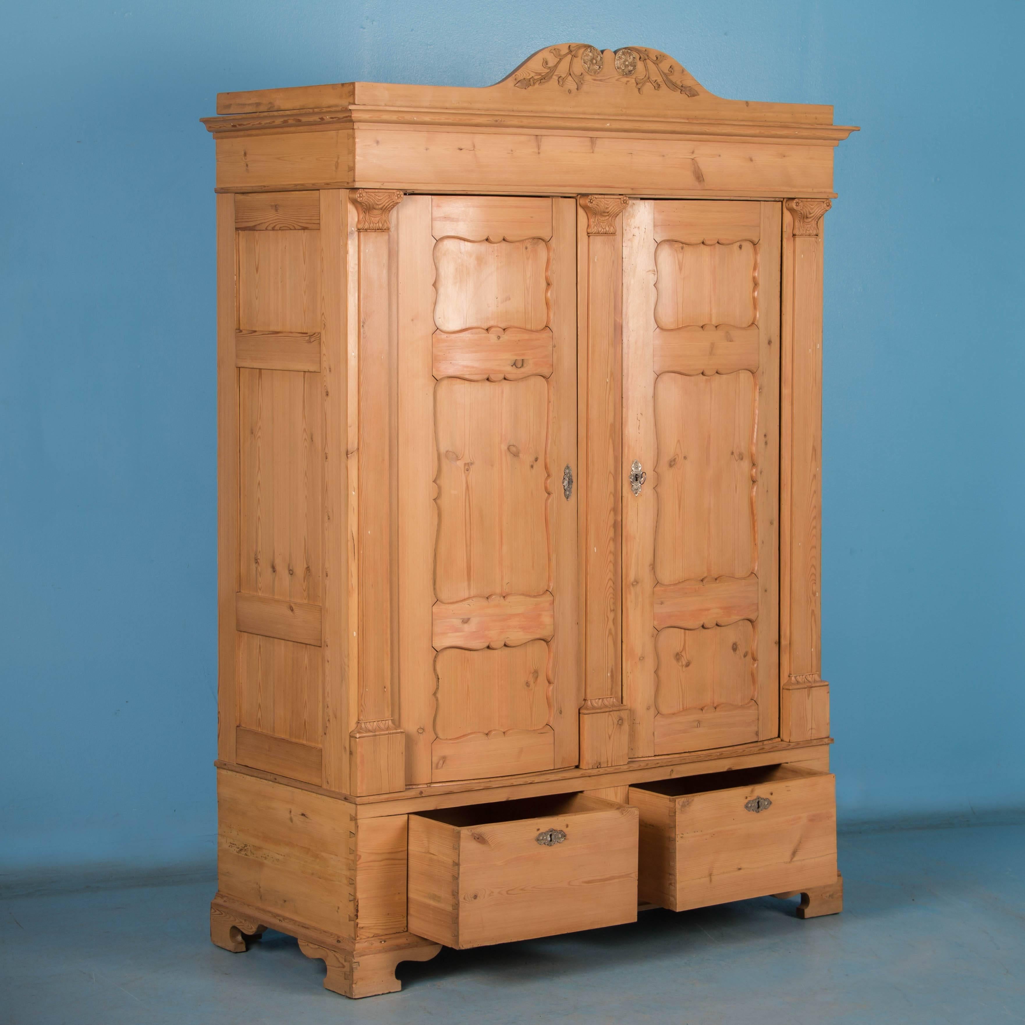 The beautiful pine seems to glow with life, taking on a warm patina from age and use in this striking armoire. Impressive in stature, this pine armoire has a strong visual presence as the eye is drawn upward to the delicate carved details of the
