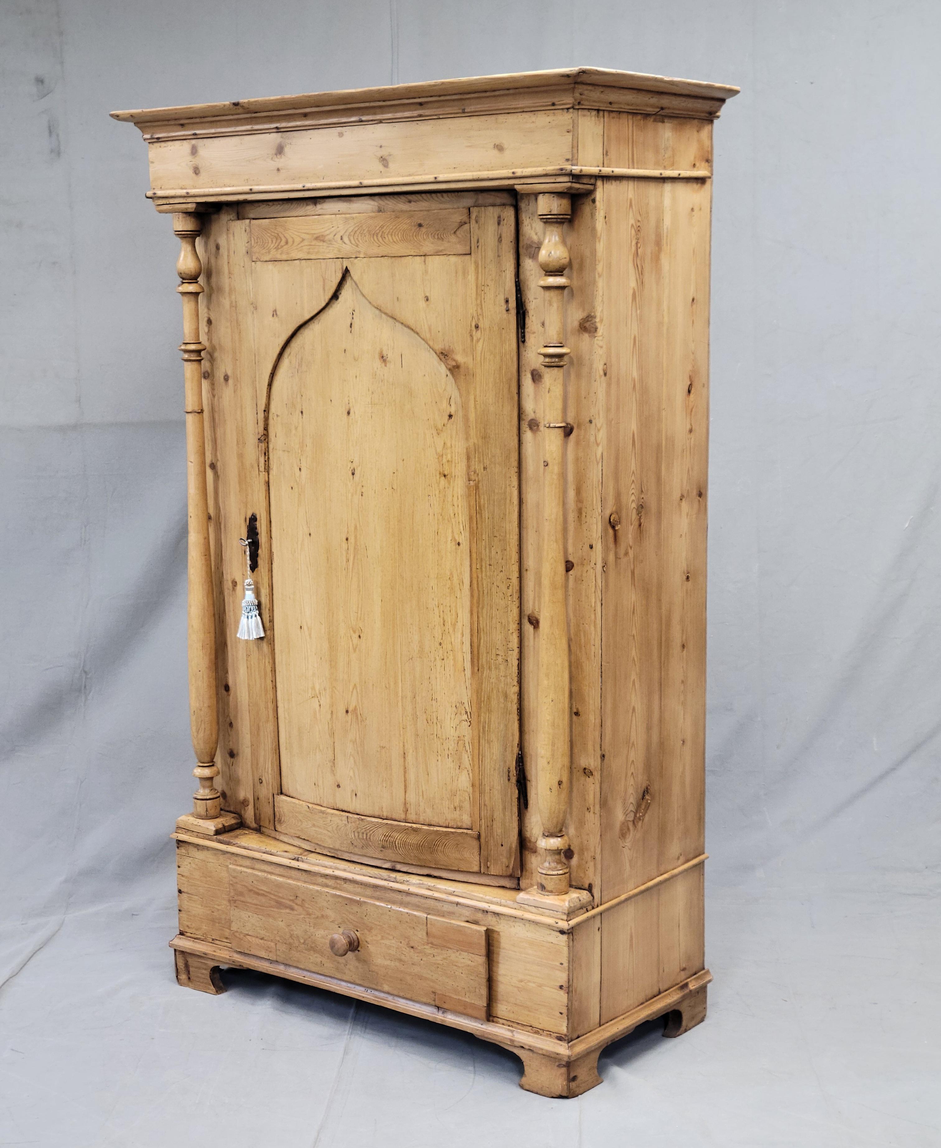 A stunning and beautifully crafted antique circa 1875 Scandinavian (likely Danish) pine armoire with bow front door and lower drawer. Pilasters adorn either side of the door while two interior shelves offer ample storage. The bow front door locks