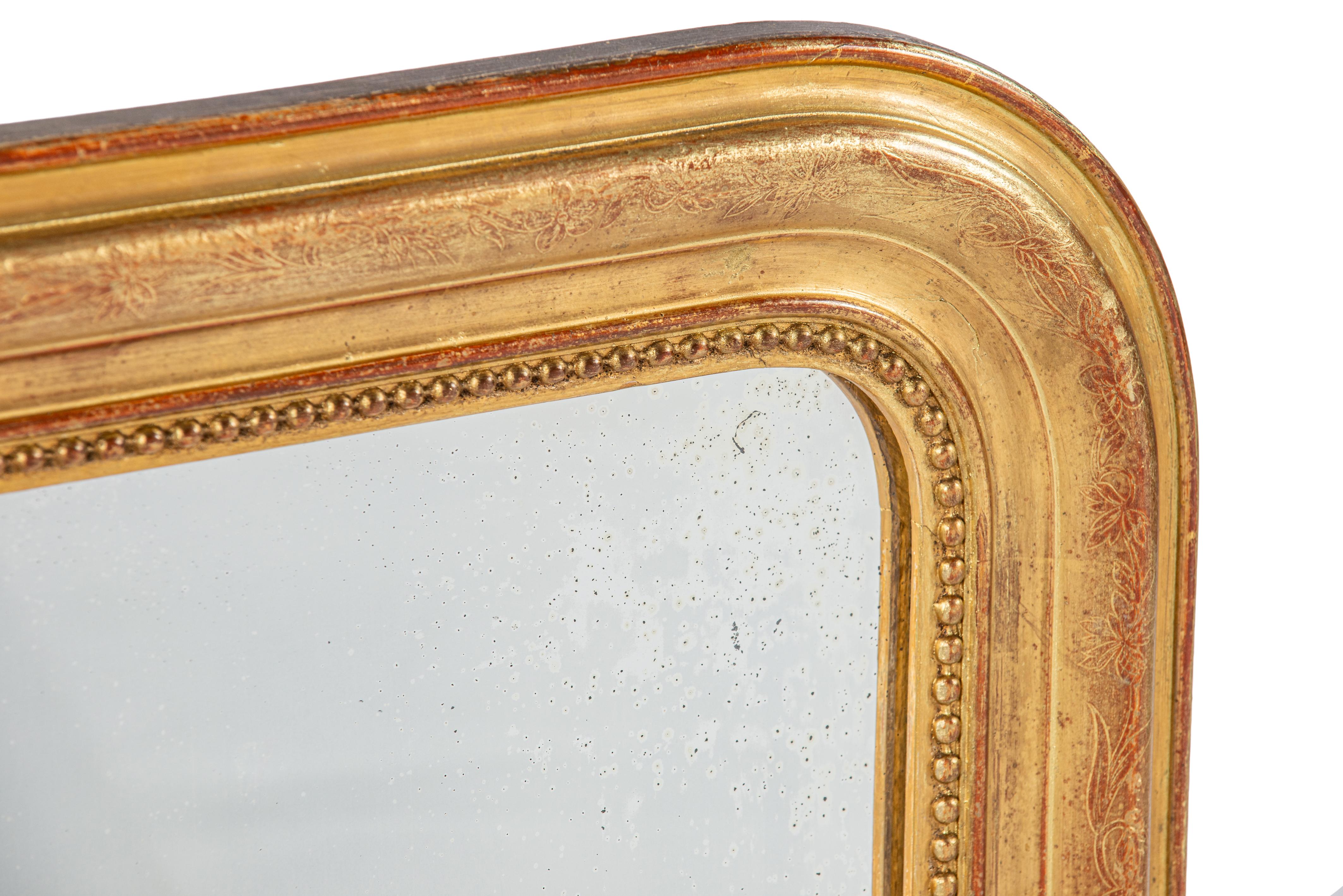 Ce miroir français ancien, daté du 22 avril 1882, est une pièce caractéristique du style Louis Philippe. Le miroir présente les angles supérieurs arrondis typiques et est entièrement doré à la feuille d'or. Avec le temps, l'or s'est légèrement usé