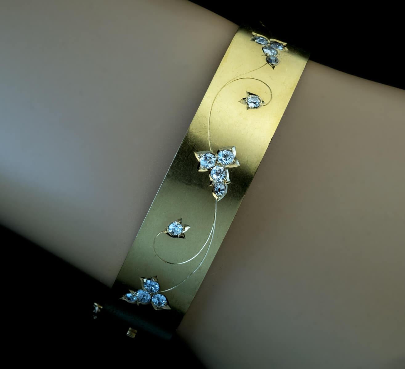 Circa 1890  Cet élégant bracelet en or jaune mat 14K est gravé de motifs floraux accentués par des diamants blancs brillants de taille ancienne (couleur E-F, pureté SI).  Le poids total estimé des diamants est de 0.80 ct.  Largeur - 13 mm (4/8 in.) 