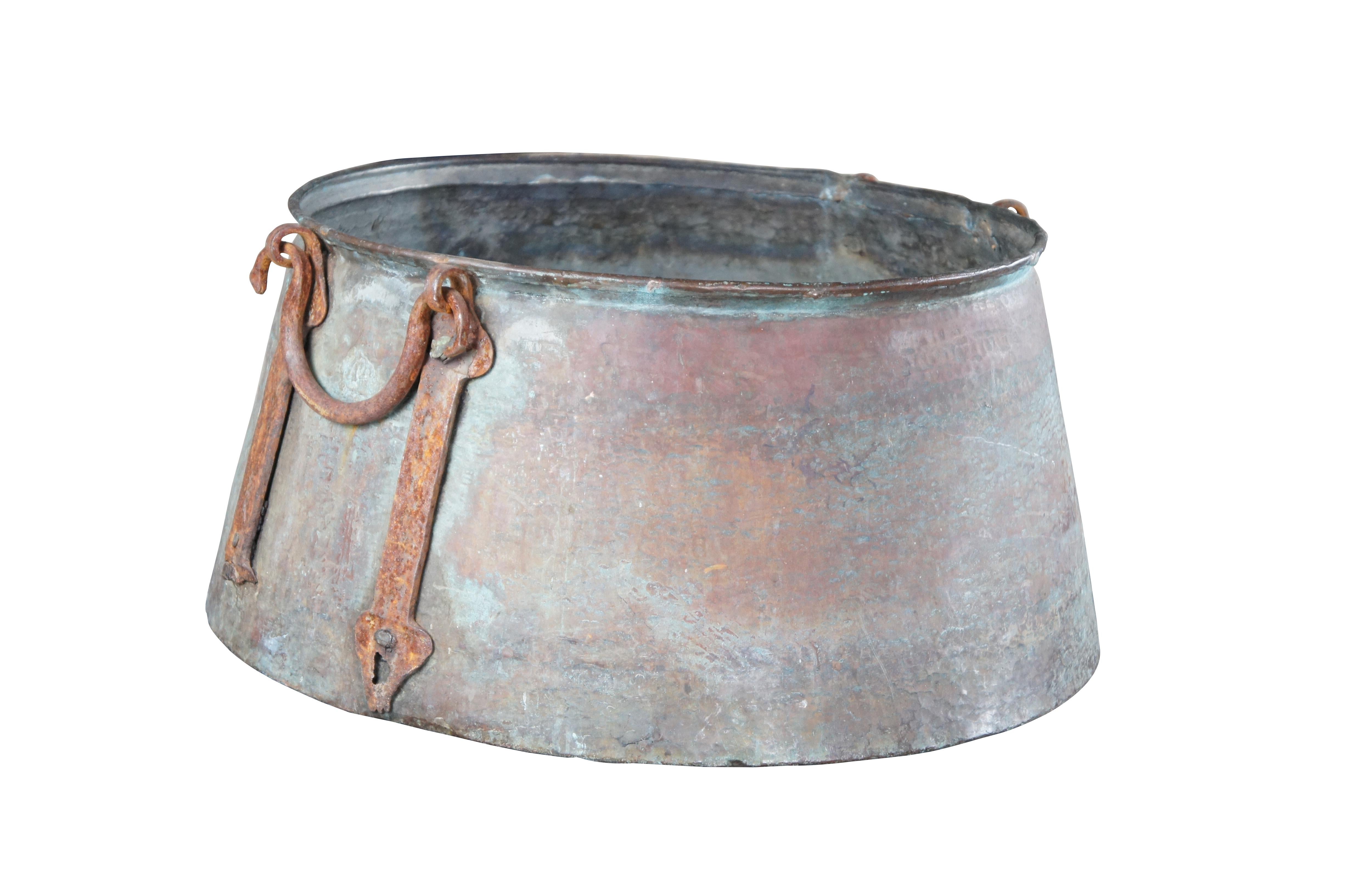 Monumental antique copper cauldron featuring hammered details with dovetailing and ornate forged iron handles.

Dimensions:
22