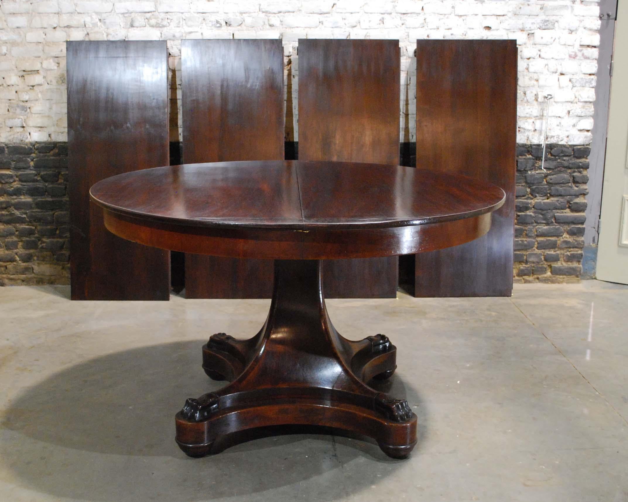 A classic Dutch Empire extension table in beautiful flamed mahogany. The table has a solid mahogany top of 0,63 inches. Below a mahogany veneered apron of 3.15 inches. The top sits on a curved tapered mahogany column that ends in claw feet. The