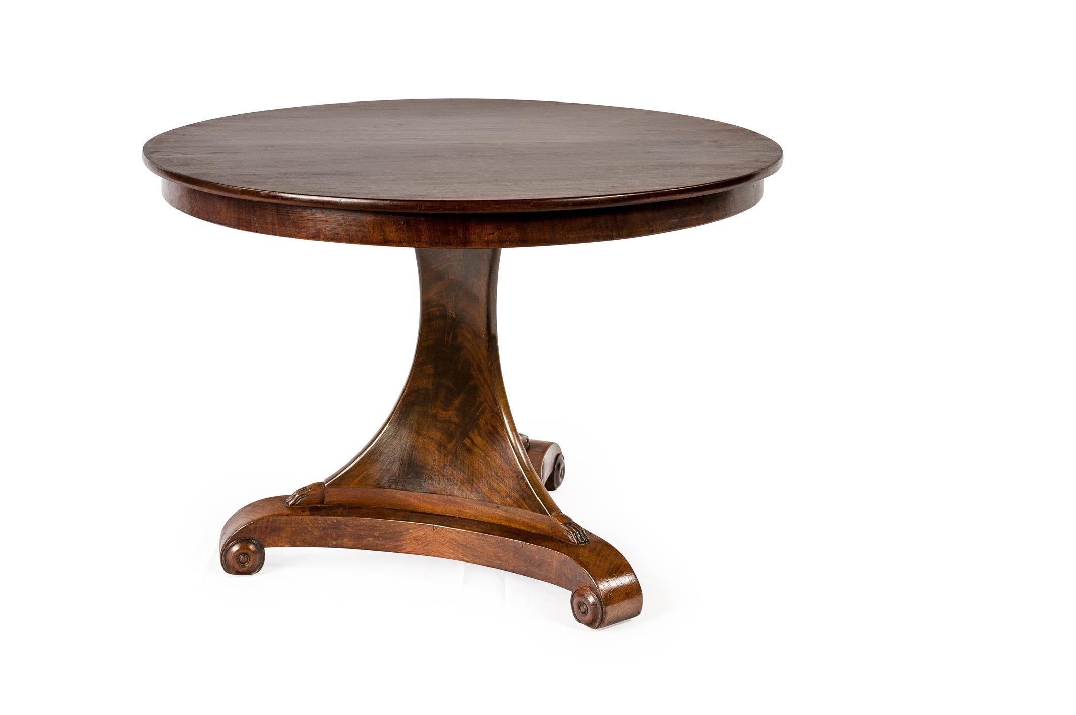 A beautiful round mahogany dining table on a trefoil platform base that ends in elegant scrolls. 
The base has a beautiful triangular column that ends in claw feet to support the tabletop. The tabletop is made in 0.8-inch thick solid mahogany in a
