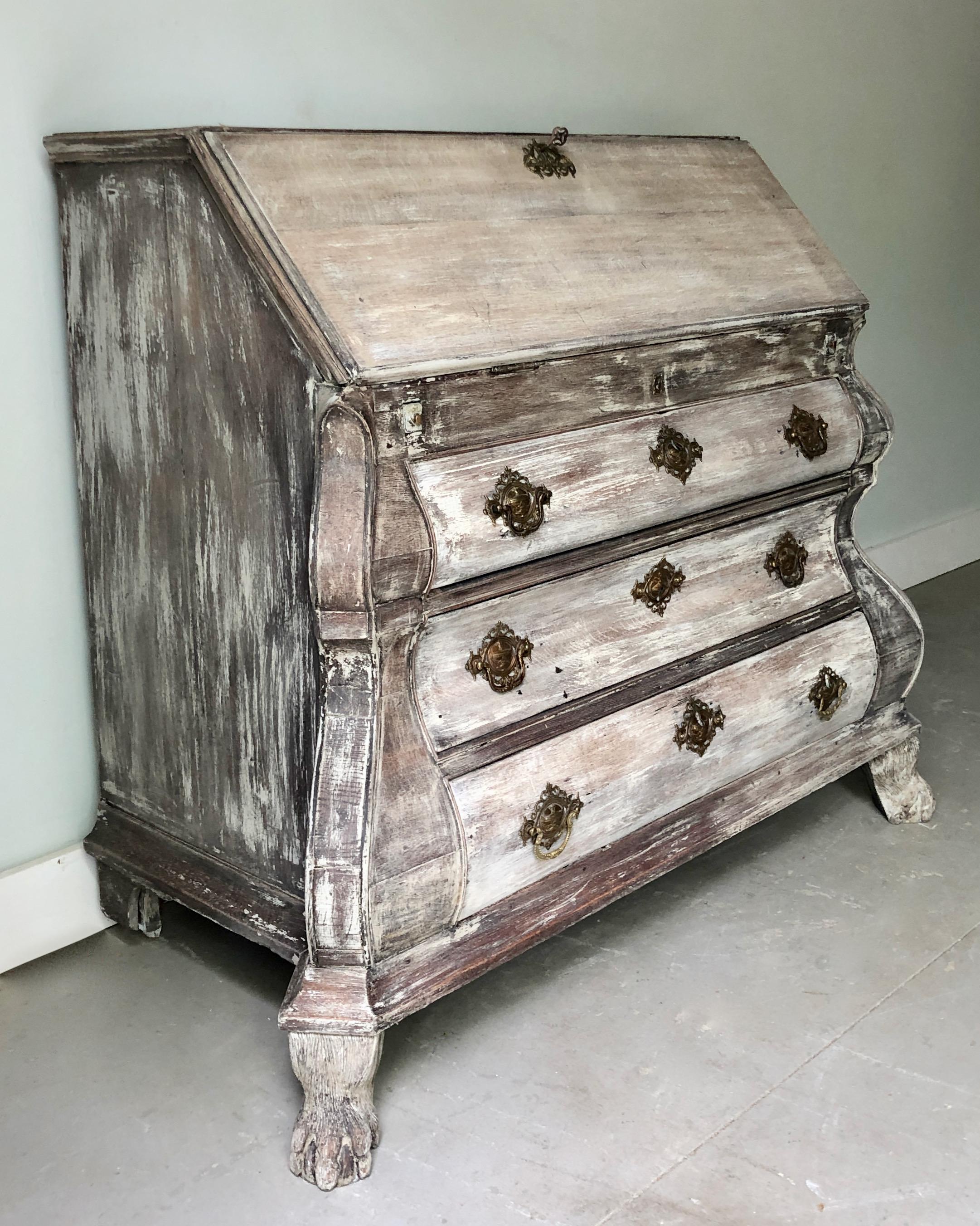 Antiguo secreter de roble holandés del siglo XIX con frente abombado de 3 cajones y patas de bola y garra talladas. El frontal abatible tiene zona de escritura y cajones escalonados y un pozo con tapa deslizante. El secretaire tiene herrajes