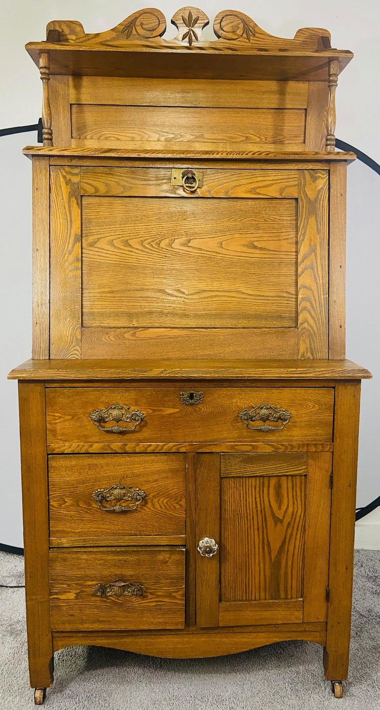 An early American 19th Century solid wood construction secretary desk made of oak. The secretary desk features a slant drop writing top , opening to reveal multiple open slots and one small drawer in the middle. 
The bottom piece offers one large