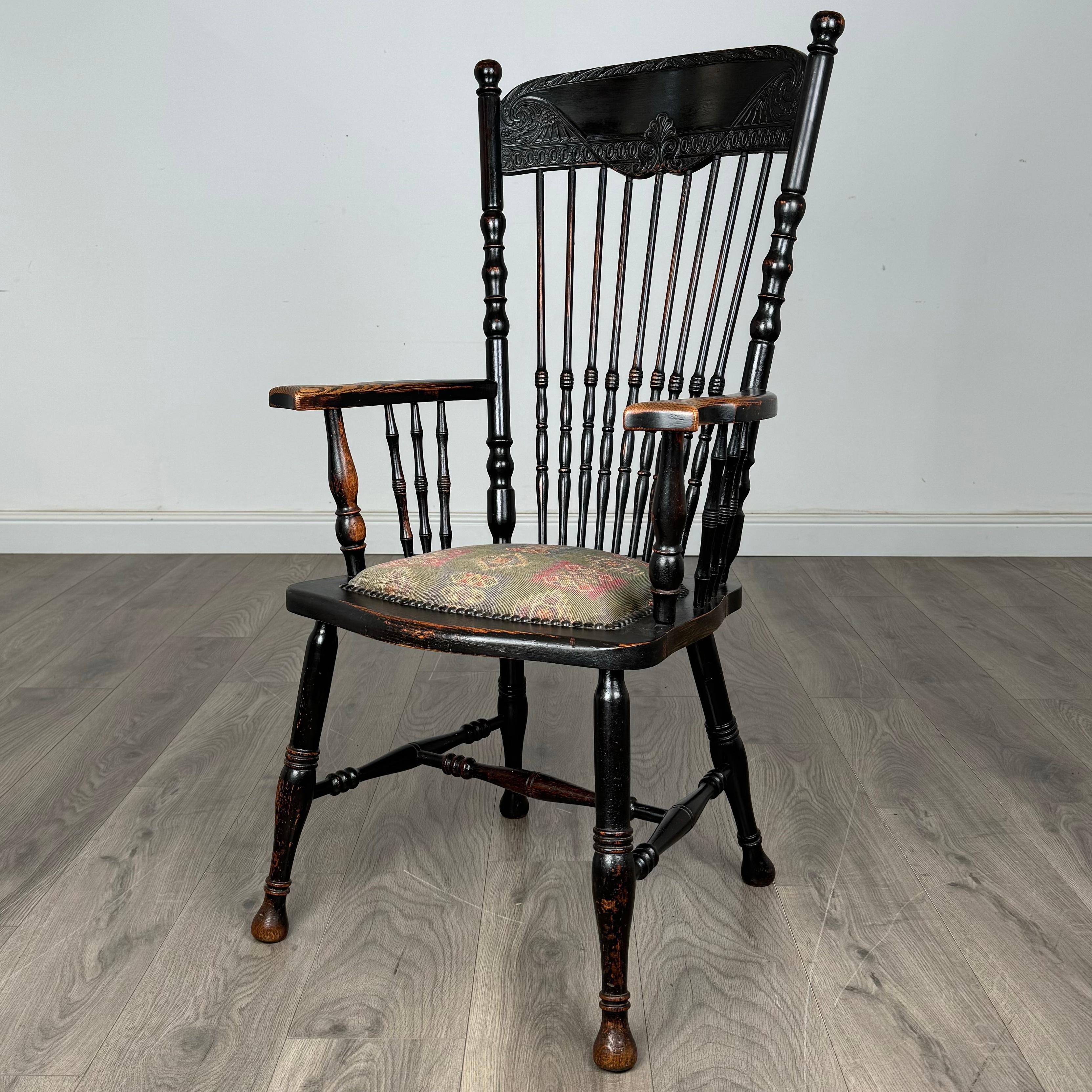 Dieser schöne Windsor-Sessel aus dem 19. Jahrhundert, der aus Eiche gefertigt und ebonisiert ist, steht auf gedrechselten Beinen, die durch eine Querstrebe verbunden sind, die sowohl Stabilität als auch klassischen Charme garantiert. Die
