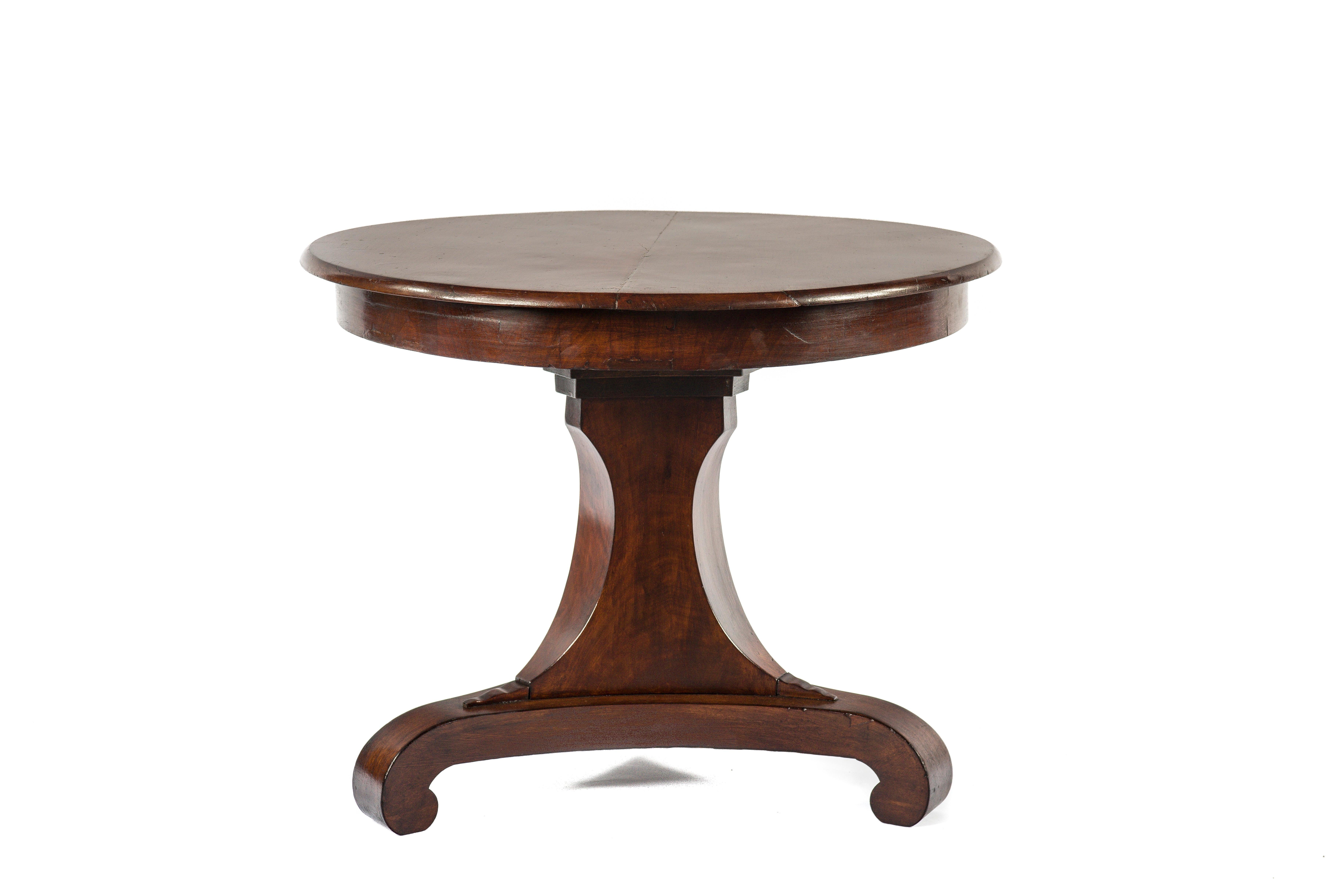 A beautiful round mahogany dining table on a trefoil platform base with facetted edges that end in elegant scrolls.
The base has a triangular facetted column made in solid oak and veneered with mahogany and ends in carved feet to support the