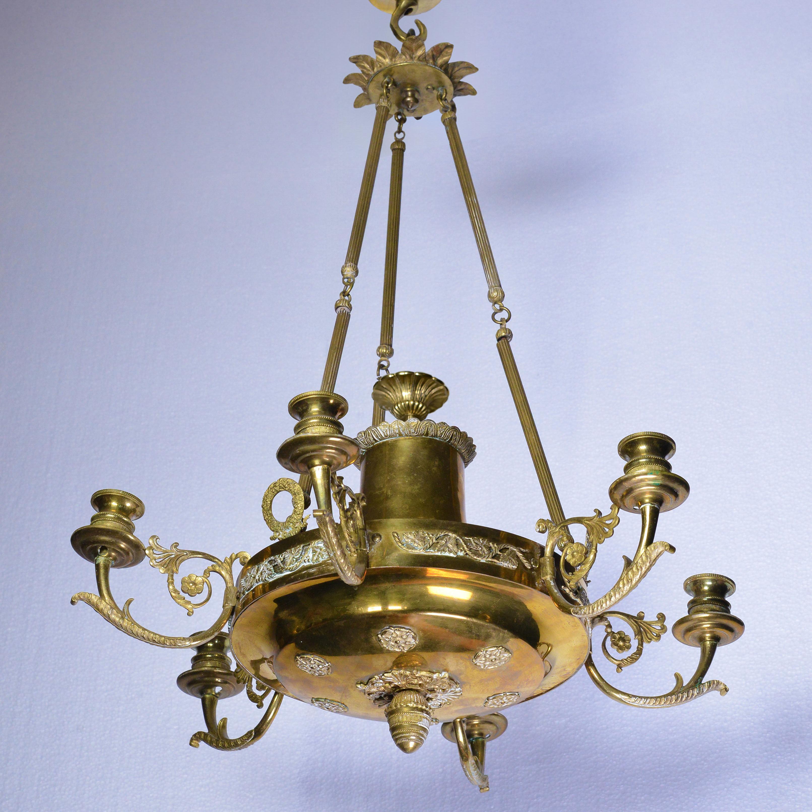 A fine Empire style gilt bronze six-light chandelier of European origin, authentic second half 19th century period piece. The central body and six elaborate candle arms are richly decorated with cast and hand-chased details depicting floral motifs,