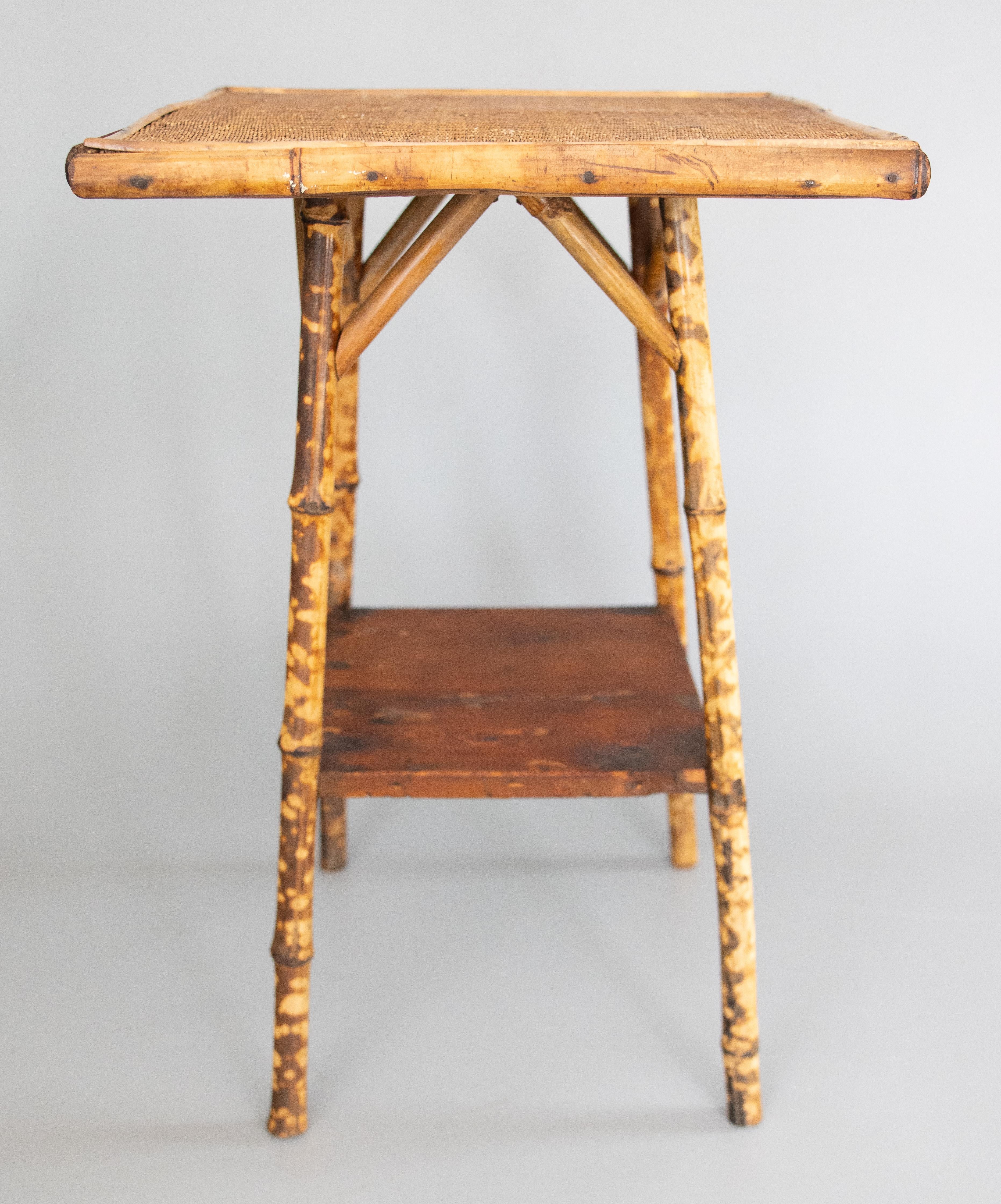 A superb antique late 19th-Century English bamboo square two tier side table. This fine table has the original lovely woven grasscloth top and beautiful tortoise bamboo legs and details. Perfect as an end or lamp table and it would make a fabulous