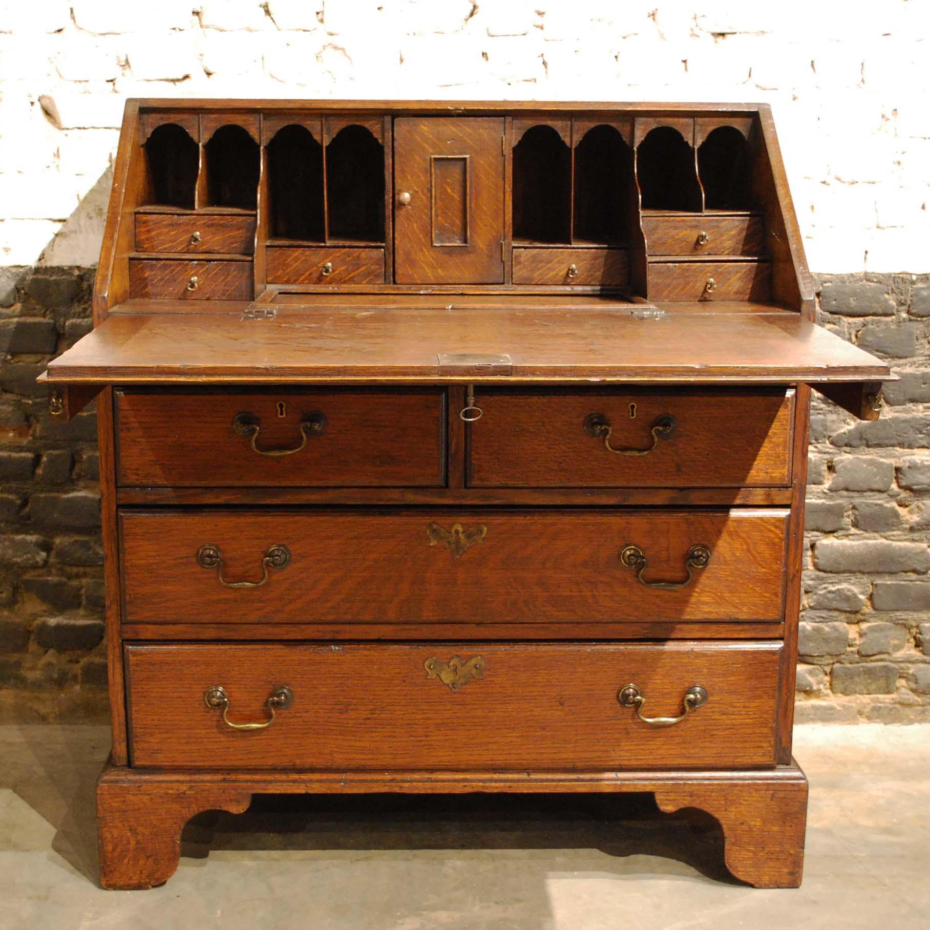 This classic slant front desk or bureau was made in England in the early 19th century.
It was made in the finest quality watered European oak. The secretary is elevated on bracket feet. It features four drawers fitted with the original brass