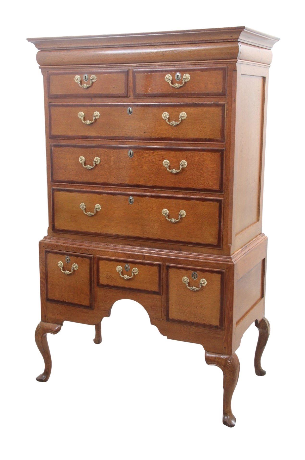 An antique English two-piece highboy dating from the late 1800's. The top cabinet houses two over three drawers, each hand dovetailed with original ornately pressed brass bail handles. Above the drawers and below the crest molding is a secret drawer