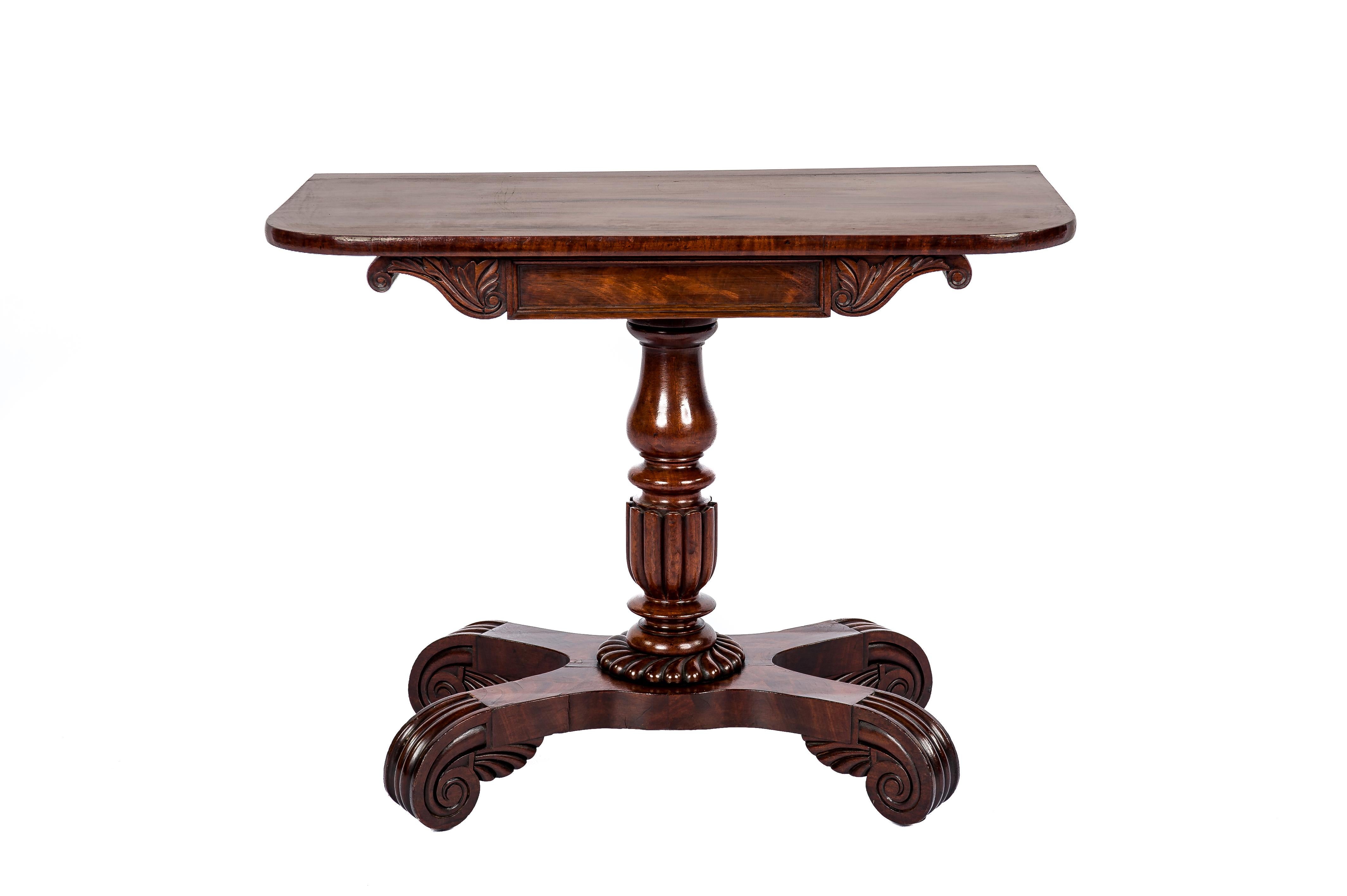 A beautiful English occasional or side table with a solid mahogany top that rests on a turned central baluster-shaped column. The central column ends in a quadriform platform with scrolled feet. The platform base is made of solid oak covered with