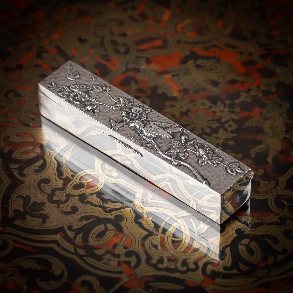 Boîte à bagues ancienne du 19e siècle en argent massif de style japonais, présentant des fleurs en haut-relief sur un fond texturé. Le couvercle à charnière s'ouvre pour révéler un compartiment doublé de velours pour ranger 9 anneaux. Cet étui est