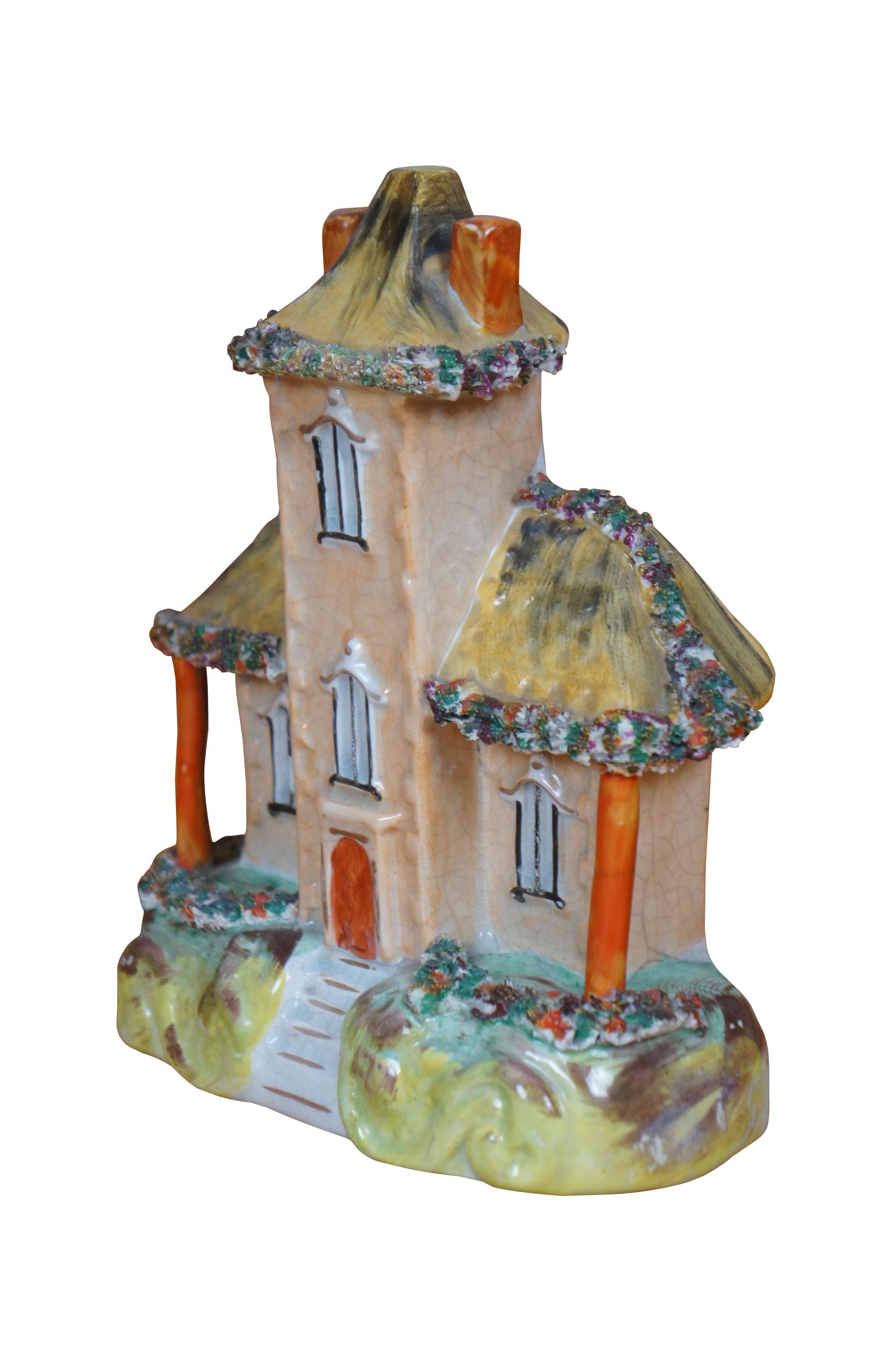 Antique 19th century Staffordshire porcelain flatback figurine in the shape of a brown stone manor house with tall central tower, two chimneys and a yellow roof, trimmed with flowers.

Dimensions:
6.5
