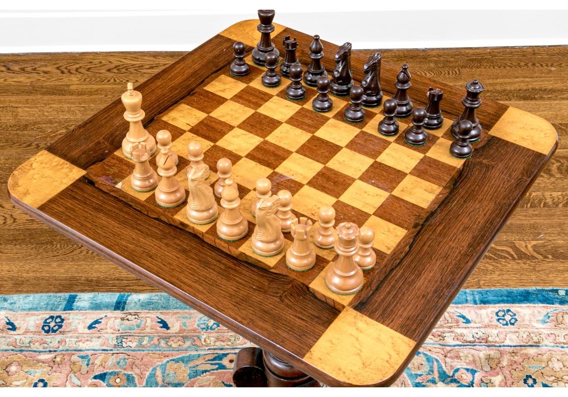 A delightful antique English tilt top games table, circa 1850-1870. Constructed of fine rosewood, burled maple, and mahogany with a fine and a stately appearance. Features a rounded corner square top over a sturdy, turned column on a tripod of
