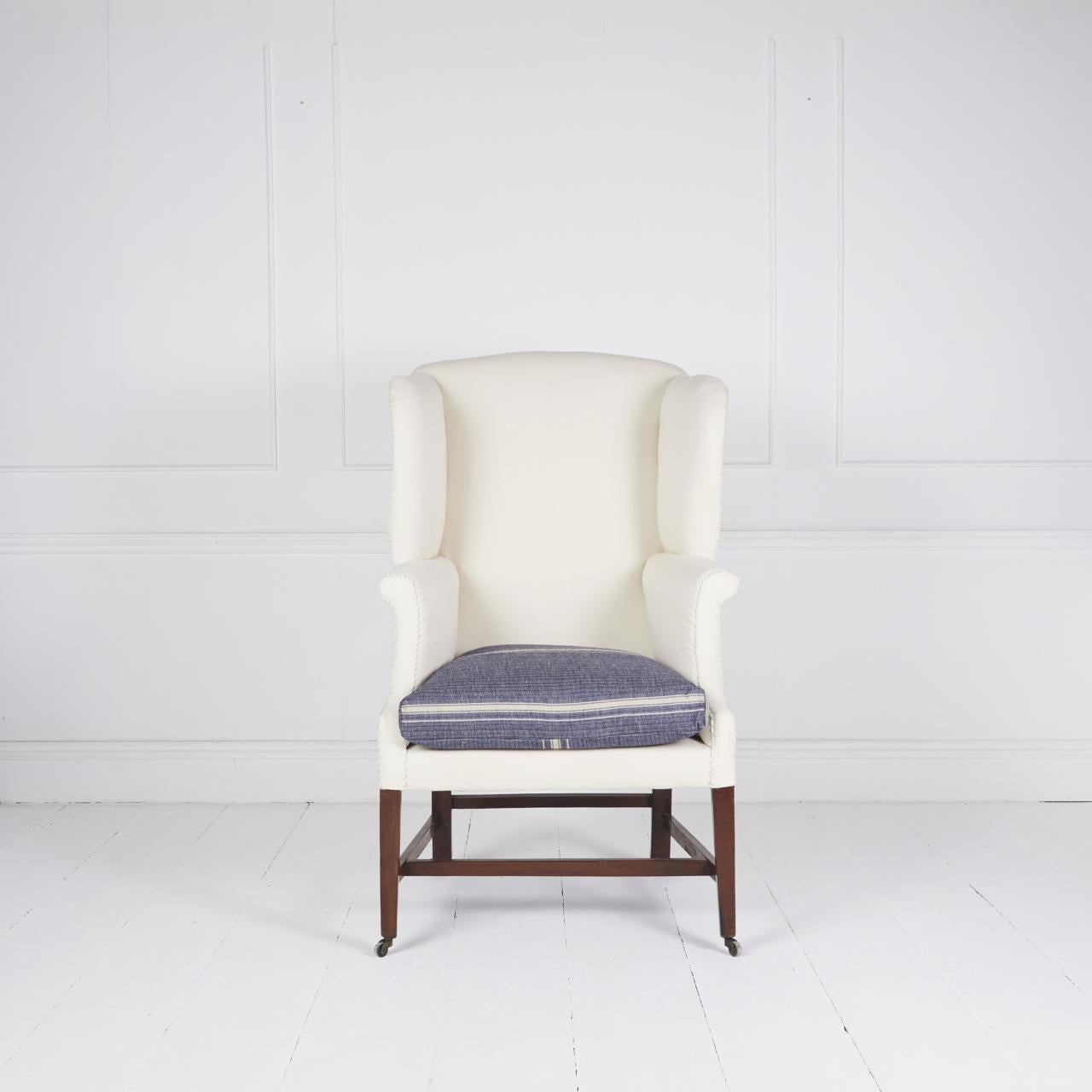 Fauteuil à oreilles recouvert de coton naturel avec coussin d'assise en plumes et duvet de canard français reposant sur des pieds fuselés en acajou, des brancards et des pieds en bois.  roulettes.

Dimensions : H 48″  L 28″ D 28″  Sh 22″ Sd 20″

Ref