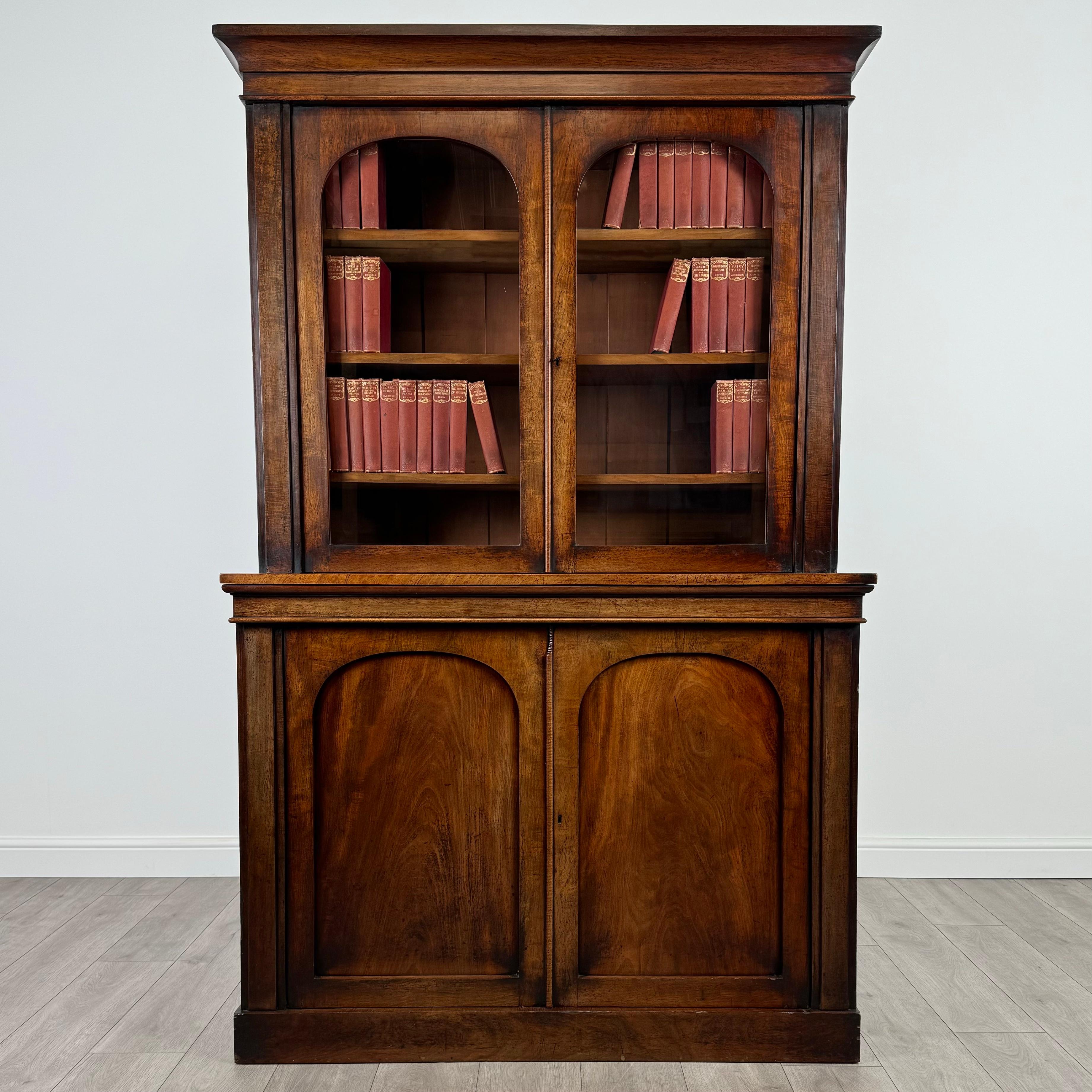 Cette étonnante bibliothèque sur armoire ancienne du XIXe siècle, fabriquée en acajou fin, est une pièce d'une qualité exceptionnelle, alliant élégance et fonctionnalité. 
Reposant sur un socle, elle présente une partie supérieure joliment vitrée