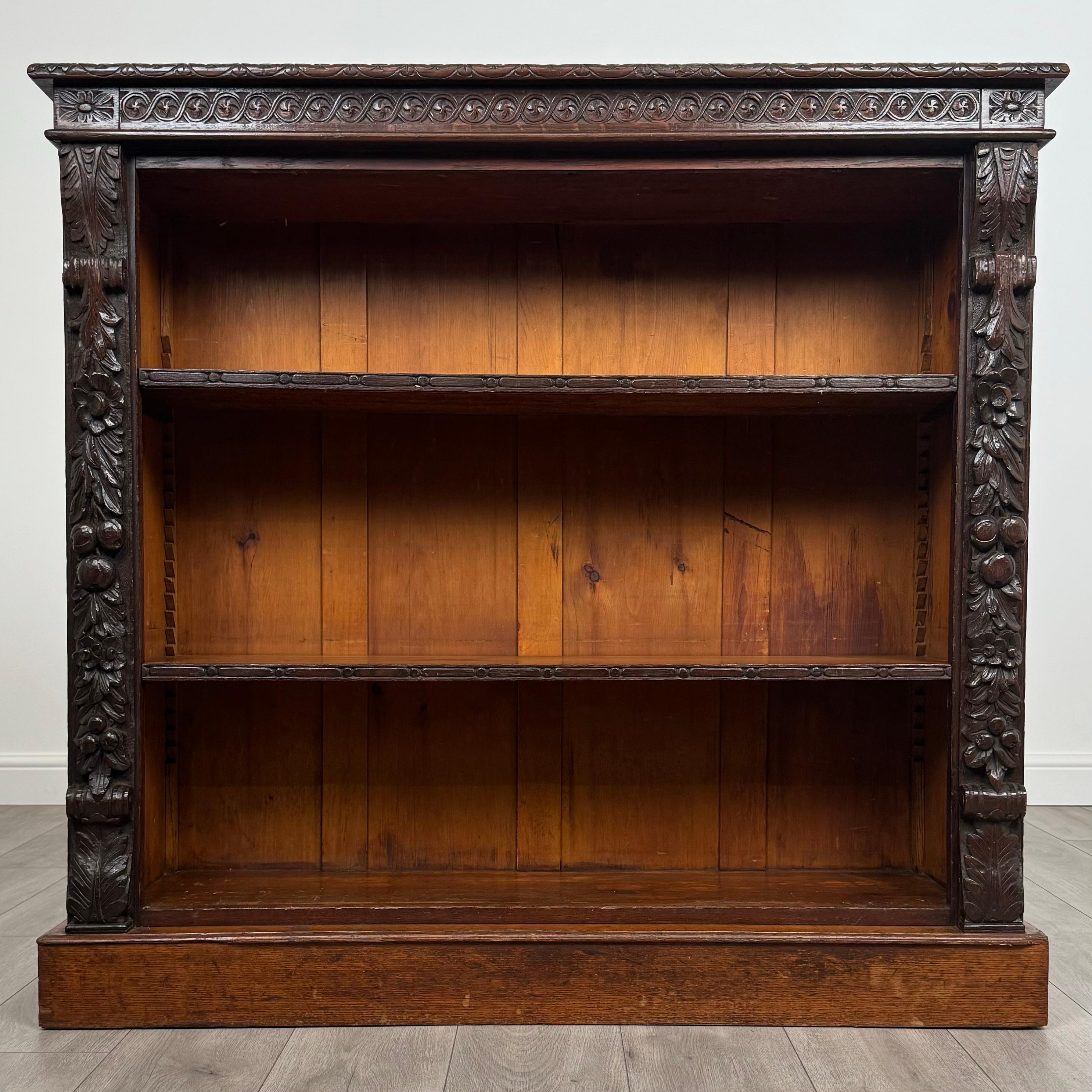 This exceptional 19th-century carved open bookcase, crafted from solid oak, is a stunning piece that combines beauty and functionality. Standing on a sturdy plinth base, it exudes elegance and is in great condition, showcasing excellent