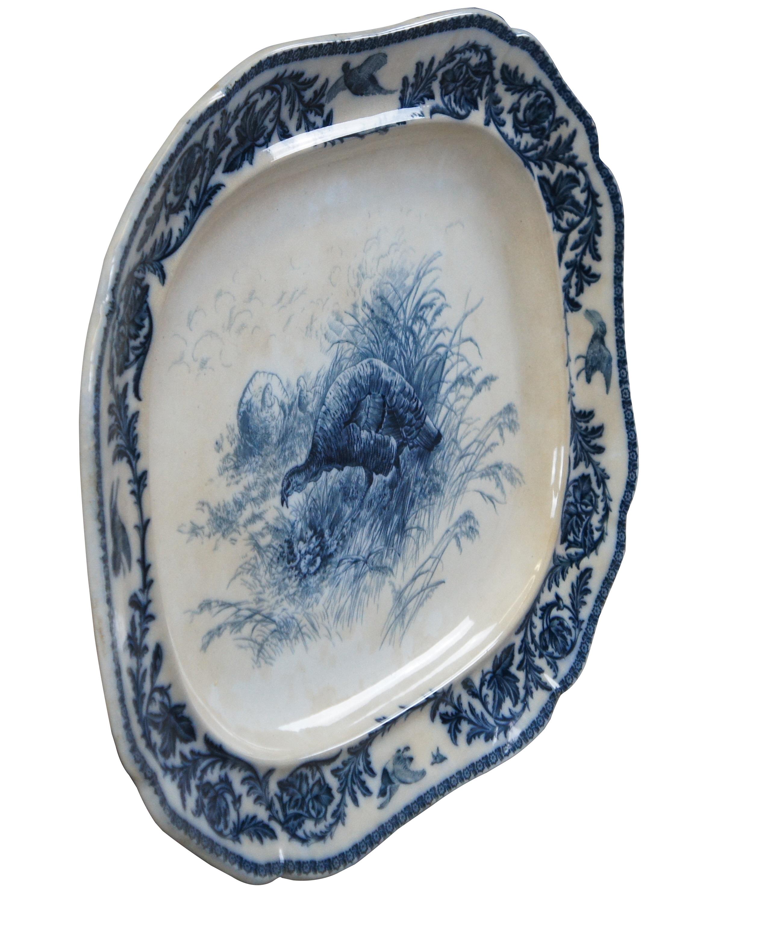 Plat à dinde en céramique bleue coulée de la fin du 19e siècle par Cauldon, fabriqué en Angleterre.  Au centre, un dindon en train de chasser est entouré de feuillages et de faisans.  Marqué Cauldon England au dos.

Dimensions :
23.5