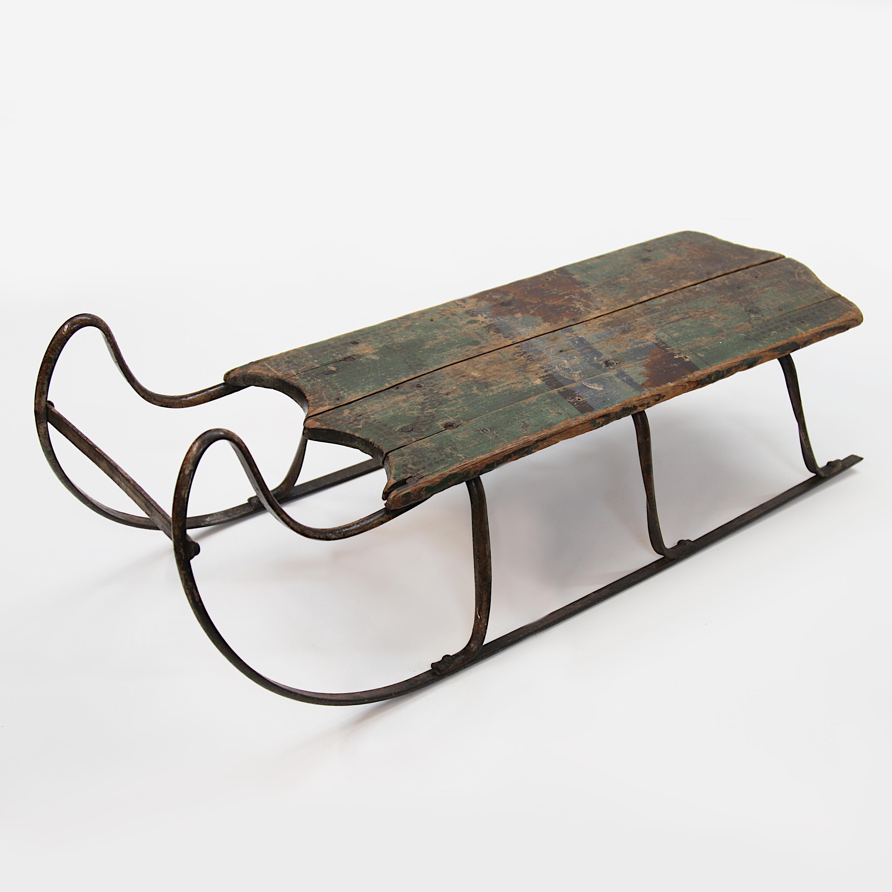 Charming child-size sled from the mid to late 19th century. Sled features forged/riveted iron runners, wooden deck, and original hand painted patina. Wonderful size and wonderful patina!