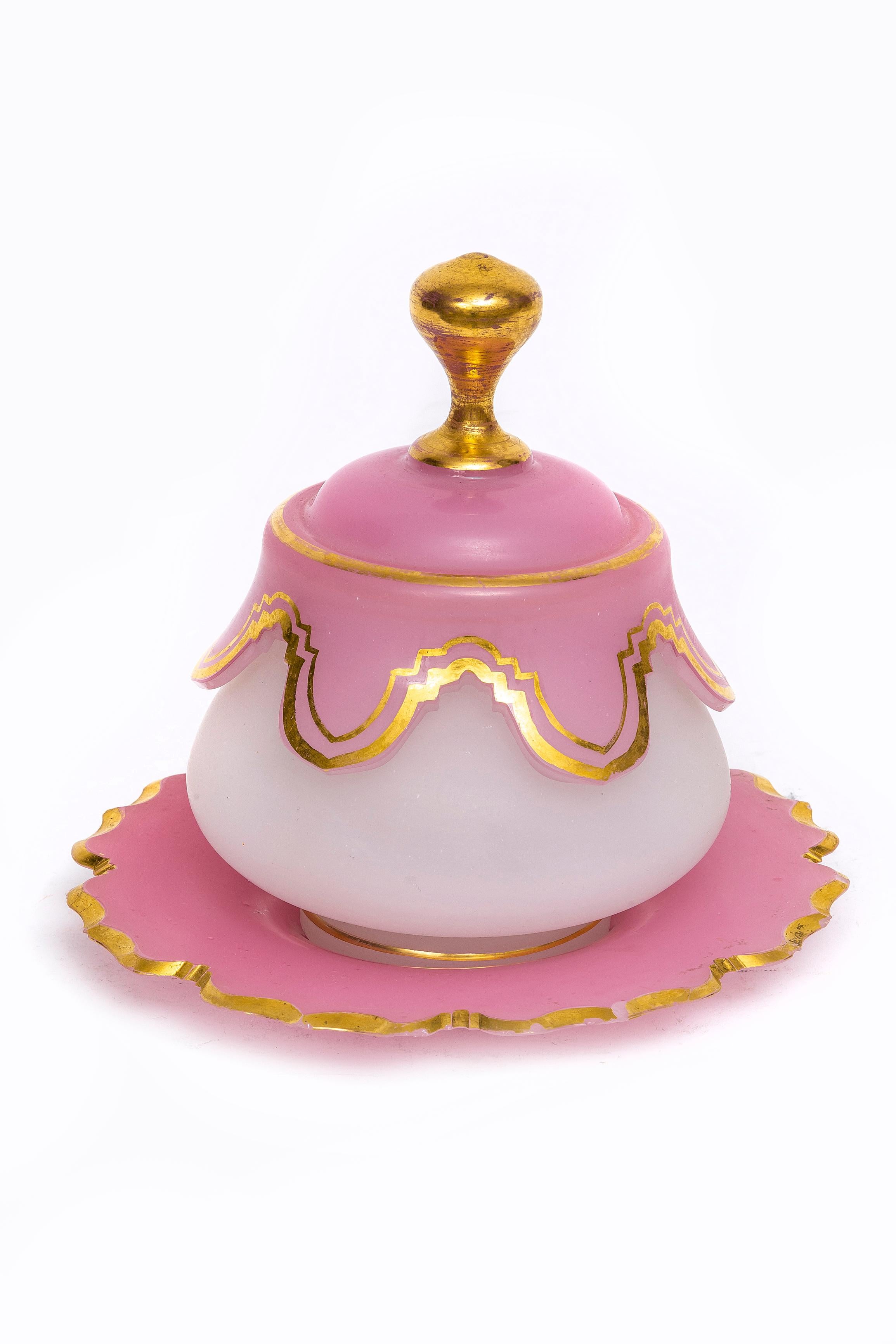 An Antique 19th Century French Baccarat Pink and White Opaline Crystal Covered Bowl with Gilt Decoration.  The bowl features a rounded base of opaque white opaline, transitioning into a pink upper section with scalloped draped detailing around the