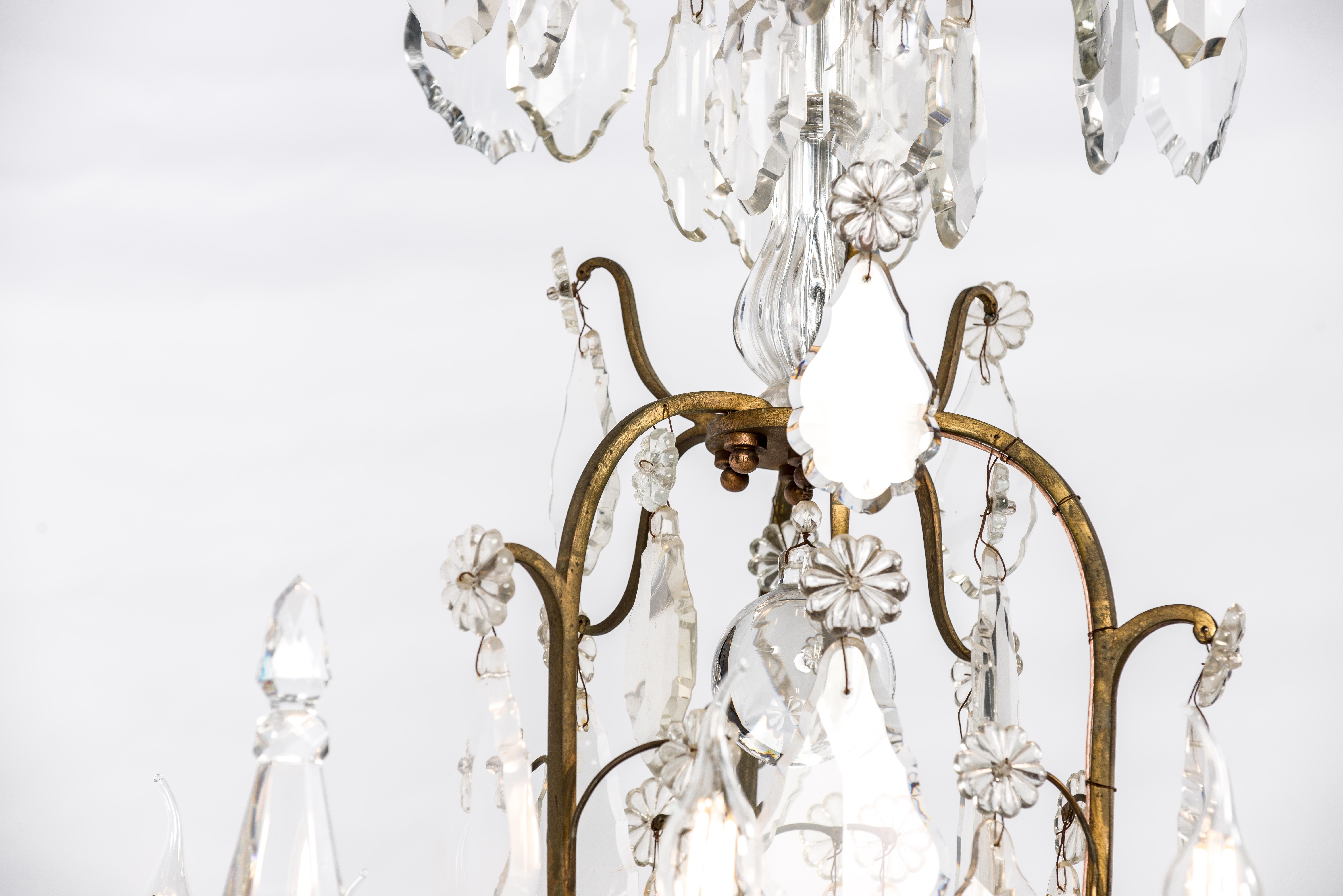 This beautiful chandelier was made in Southern France around 1850. It has a forged brass fire gilt open cage frame and is hung with the highest quality clear crystal cut ornaments. The crystal ornaments are thick, large, and were beautifully cut