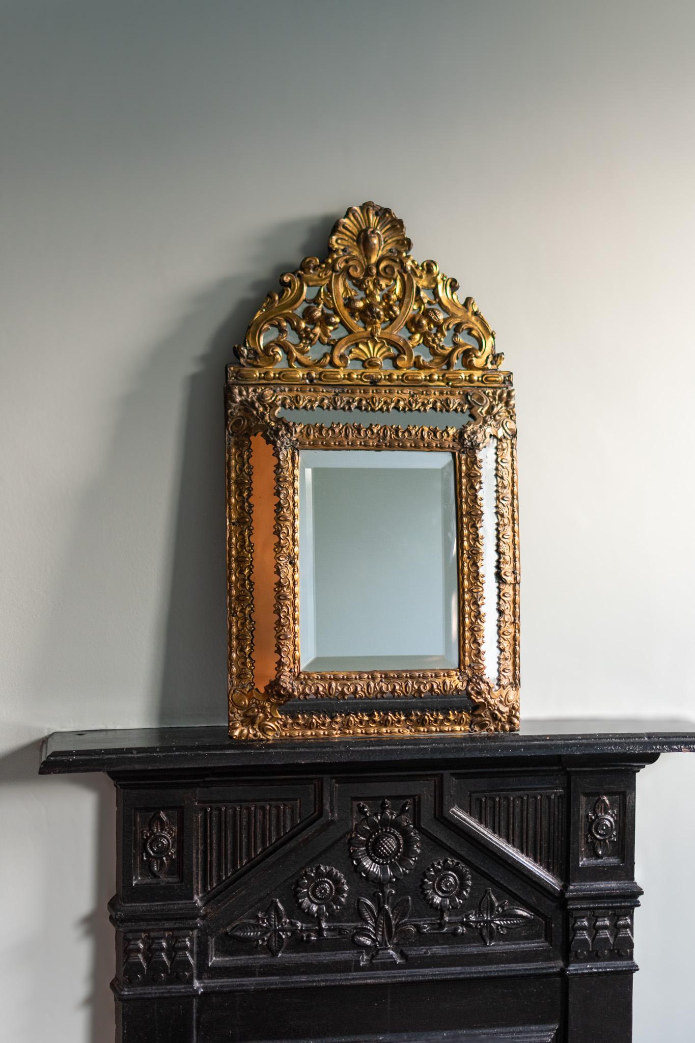 A beautiful late 19th century French Napoleon III style antique mirror dating around 1880. Made from solid wood with a beaten brass surface decorated with various geometric and floral motifs. The mirror is bevelled glass.

Condition: Visible repair