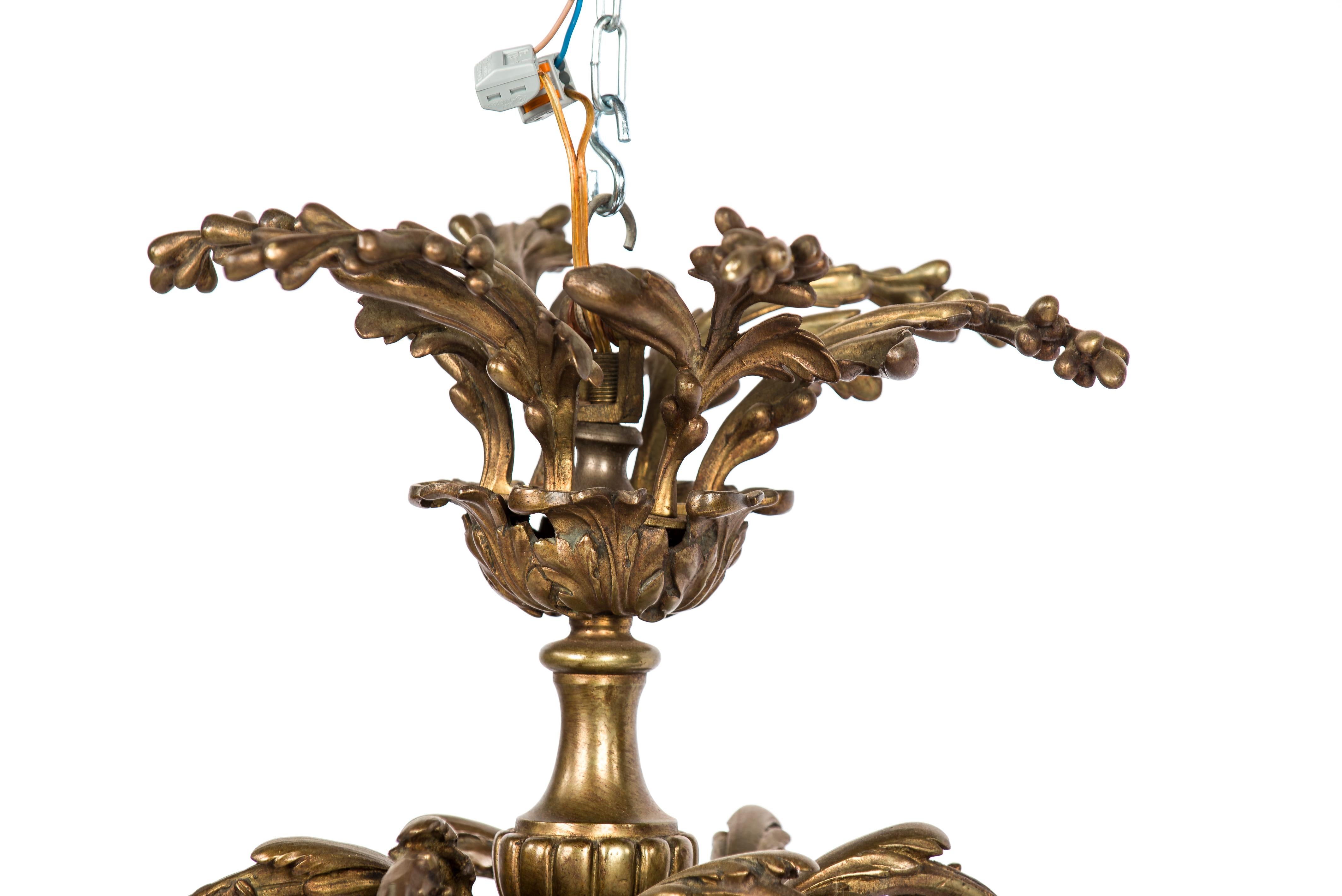 This beautiful compact chandelier was made in France in the late 19th century. The pendant features 6 asymmetrical shaped arms decorated with scrolls and acanthus. The central turned column of the lamp is decorated with a gadrooned mold, acanthus,