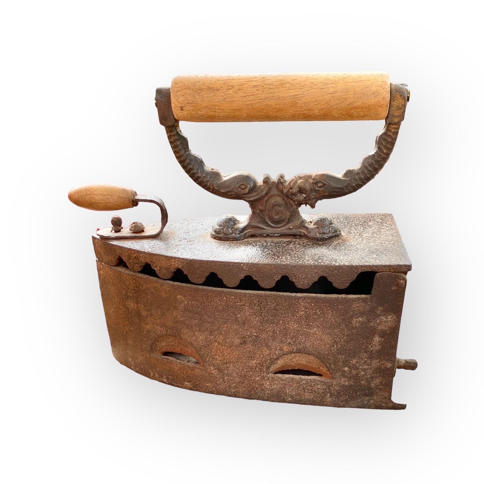 A charming antique 19th century French iron and wood coal iron with an unusual dolphin decorated iron and wood handle from the provinces of France. 