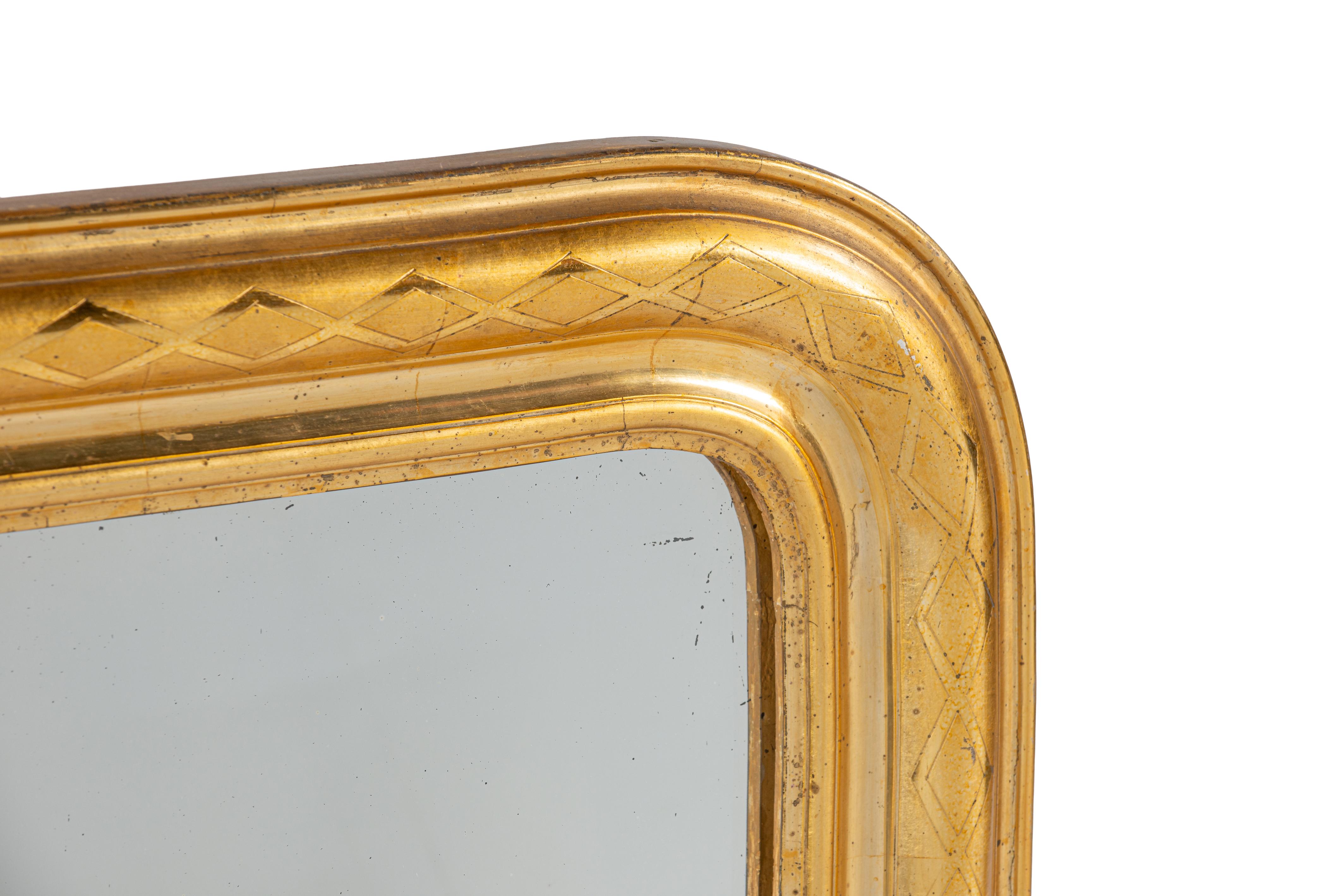 Elegant Louis Philippe mirror with its original gilding, made in France around 1850. The mirror features the characteristic rounded top corners and flat bottom, typical of the period. This shape is a hallmark of the Louis Philippe style, named after