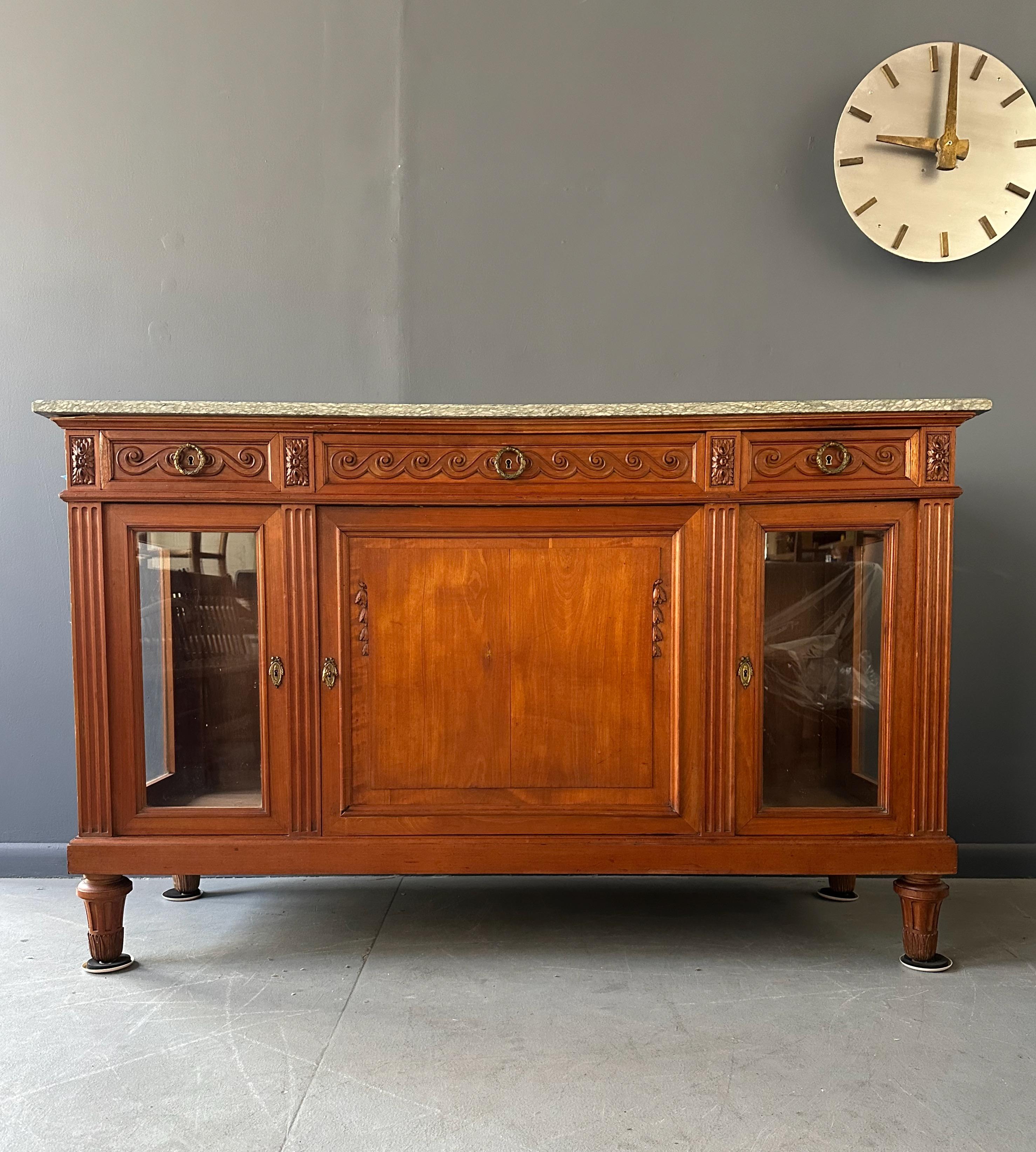 Elaborado con maestría al estilo Directoire, este aparador antiguo presenta una lujosa encimera de mármol y rica madera de cerezo. Creo que esta pieza no empezó su vida así. Los paneles de cristal parecen ser sustitutos de paneles de caoba, tal vez.
