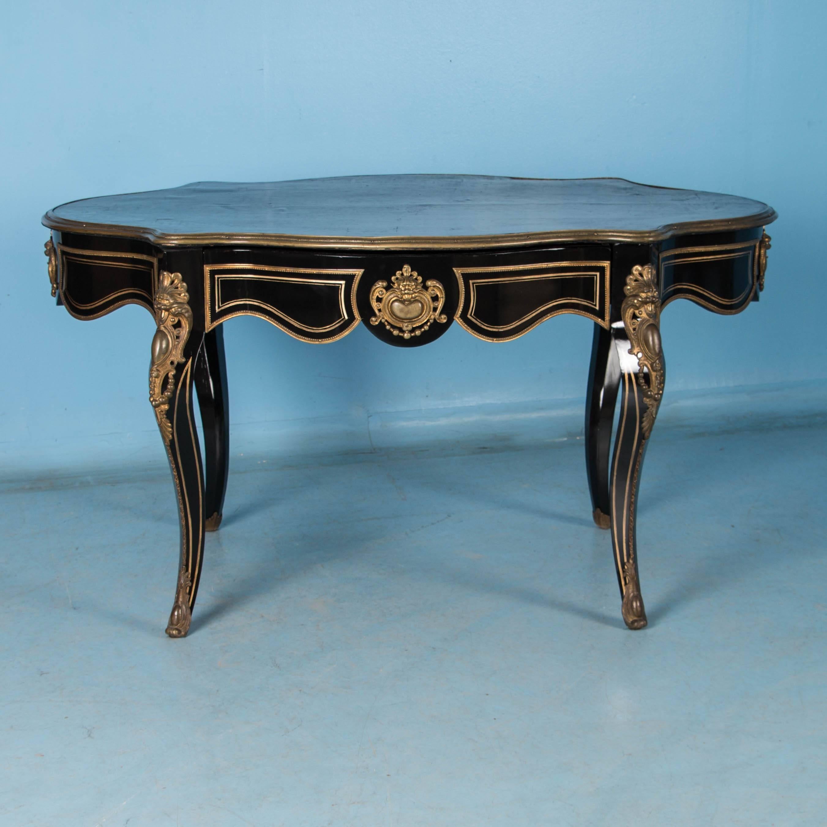 This elegant French Louis XV style ebonized desk features ornate gilt brass ormolu mounts and cabriole legs. The desk is freestanding which allows one to appreciate the elaborate brass details on all sides. The dark green leather has a deep aged