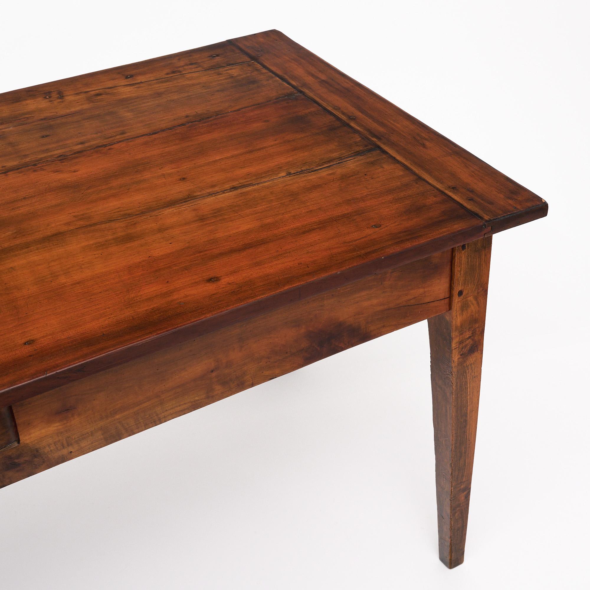 Table de ferme française en bois massif, principalement en noyer. La table présente les lignes provinciales classiques des meubles de ferme français. Un tiroir à queue d'aronde se trouve sur un côté, avec un bouton en bronze. Nous aimons la nature