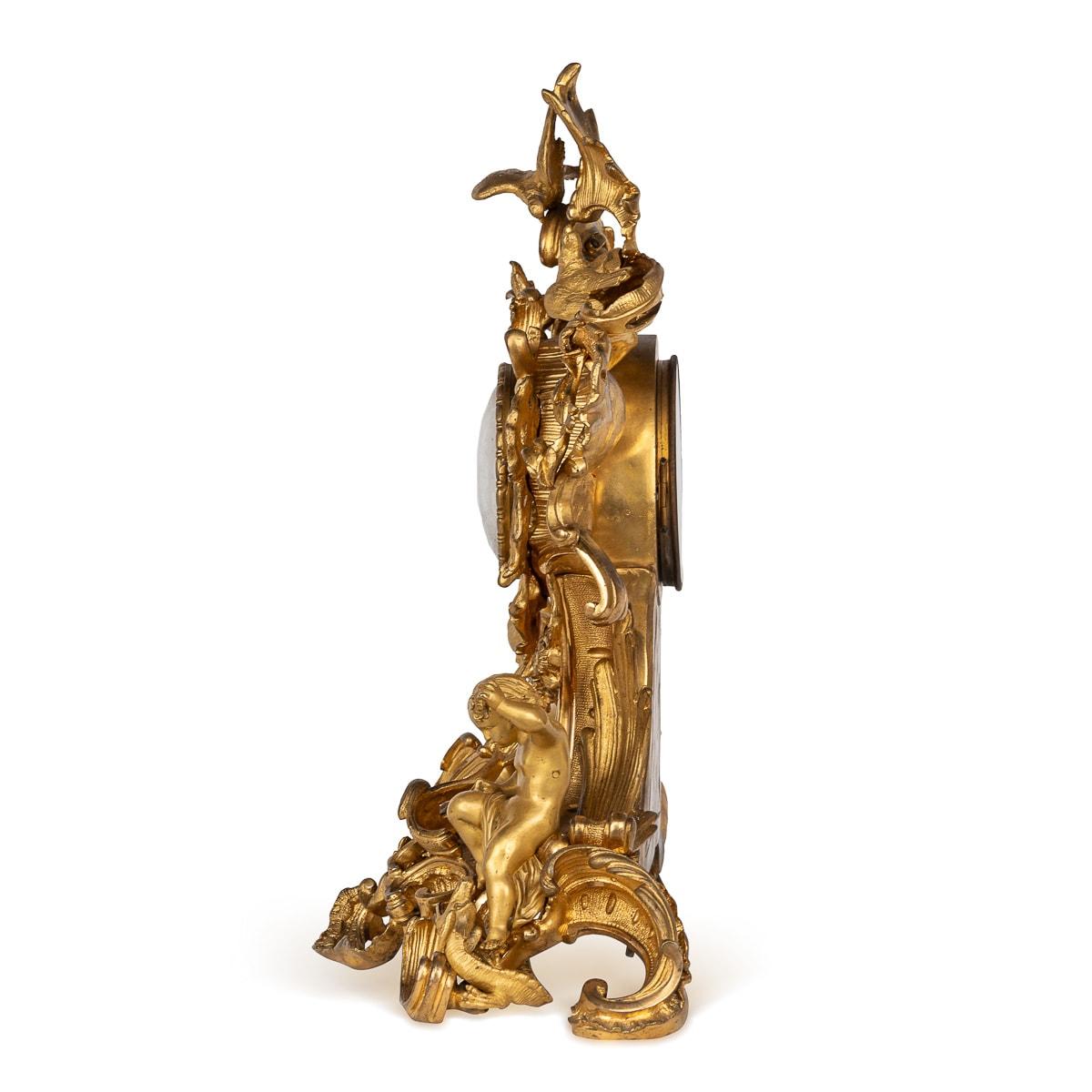 Antiques 19th Century French Rococo-style gilt-bronze mantle clock crafted by Raingo Frères. The clock boasts intricate decoration throughout, with birds resting on floral foliage adorning its surroundings. Flanking the central column on the base