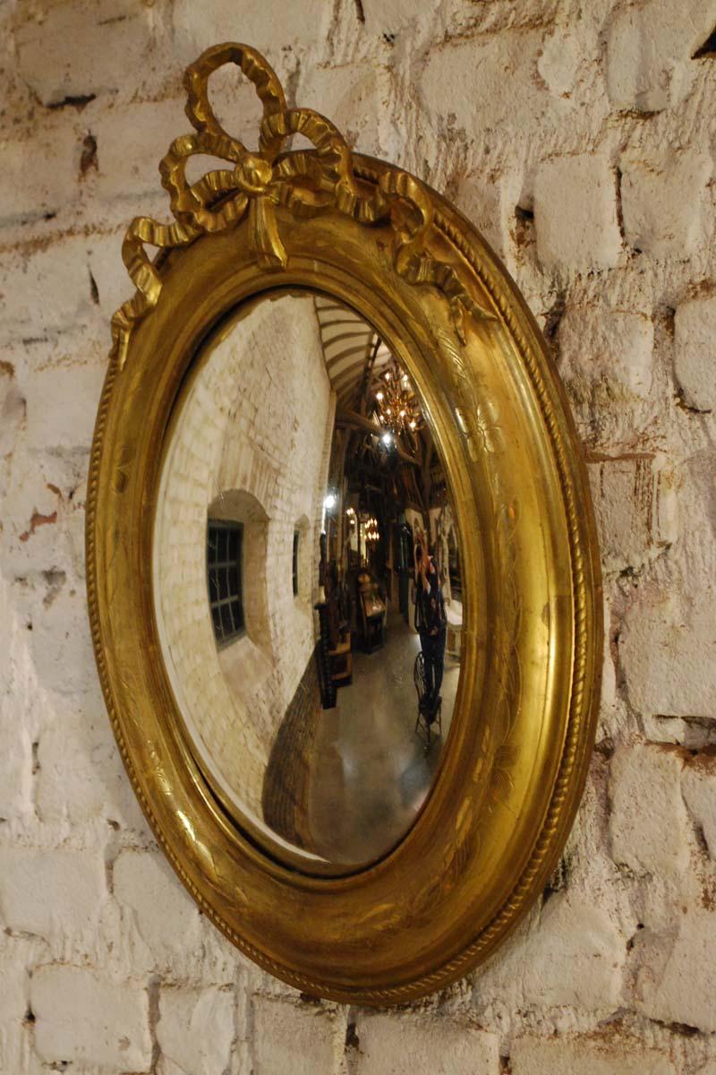 A beautiful 19th century convex mirror in Louis Philippe style. 
It has a solid pine frame, smoothened with gesso. A finely carved floral engraving on the most elevated part of the frame. The gold leaf gilding of the engraved parts are much more