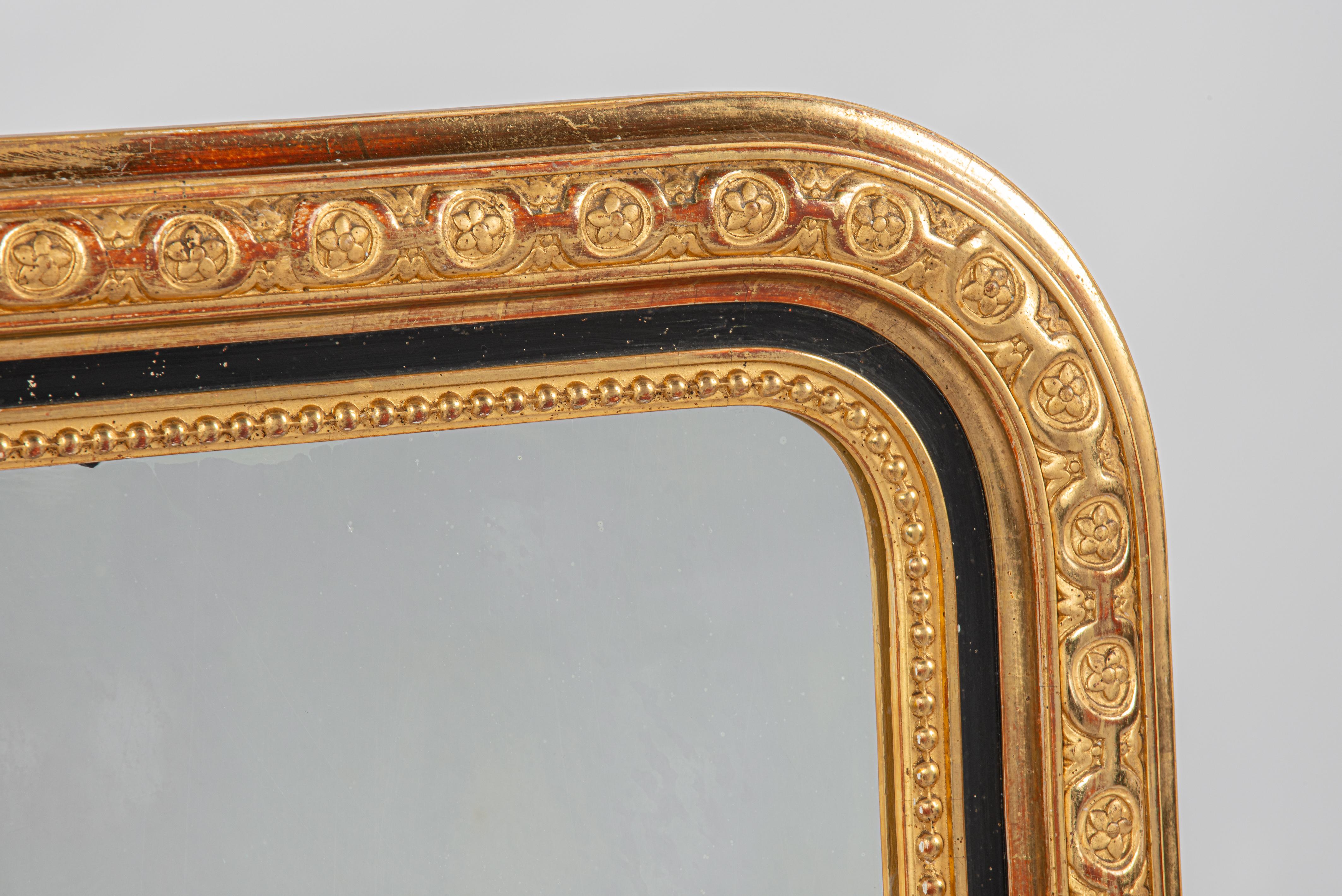 Hier wird ein wunderschöner antiker, blattvergoldeter Louis Philippe-Spiegel aus Südfrankreich angeboten. Dieser Spiegel stammt aus der Zeit um 1870 und weist oben abgerundete Ecken auf, die für den Louis-Philippe-Stil charakteristisch sind. Es wird