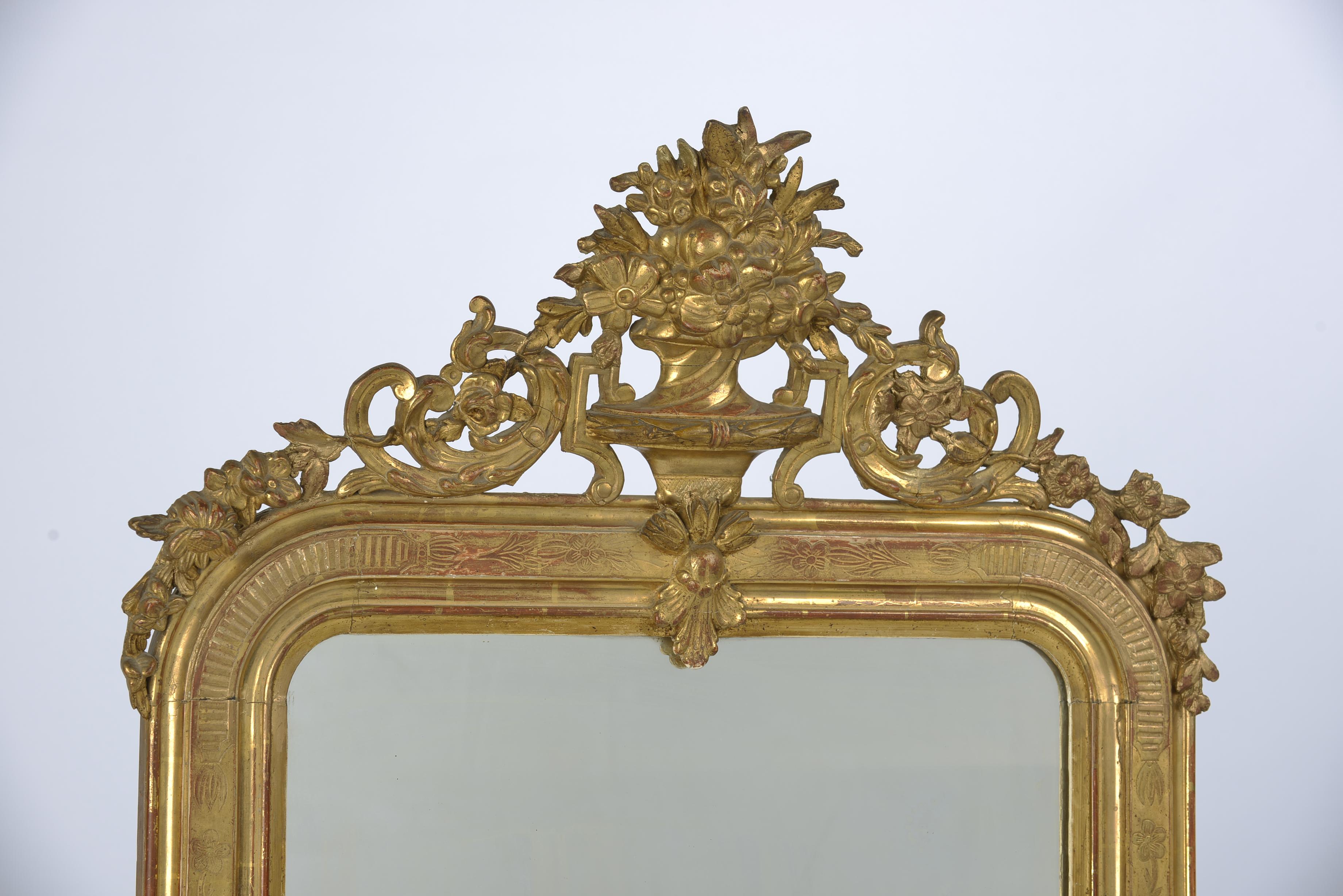 A beautiful antique mirror that originates in France, circa 1890.
The mirror has the upper rounded corners typical for Louis Philippe mirrors. The mirror has a rich, ornamented crest with a central goblet with flowers flanked by acanthus and