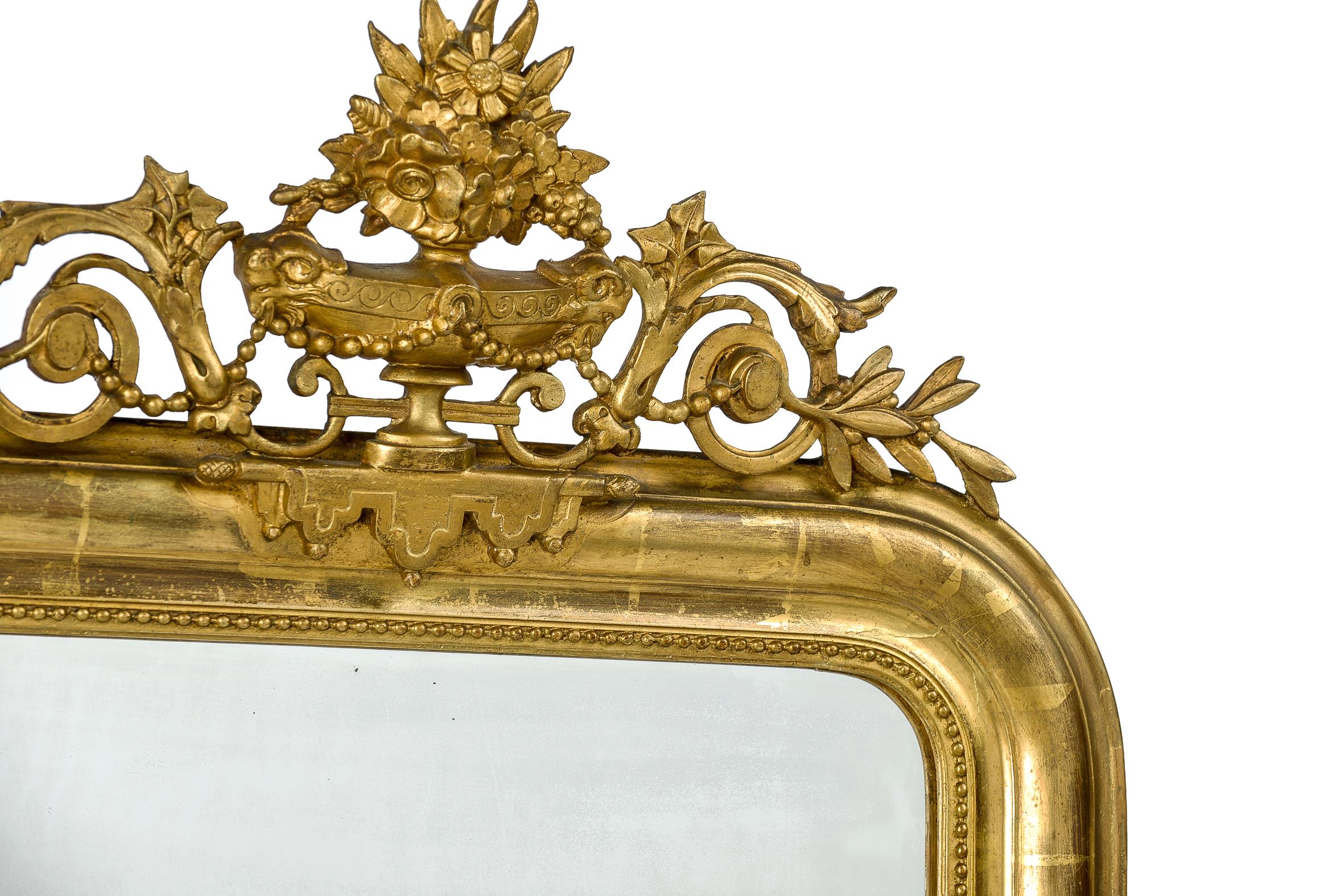 This beautiful antique mirror was made in France around 1880. It is a pure Louis Philippe mirror with its upper rounded corners and elegant frame. The most elevated part of the frame has a floral engraving on both sides and a classic pearl beading