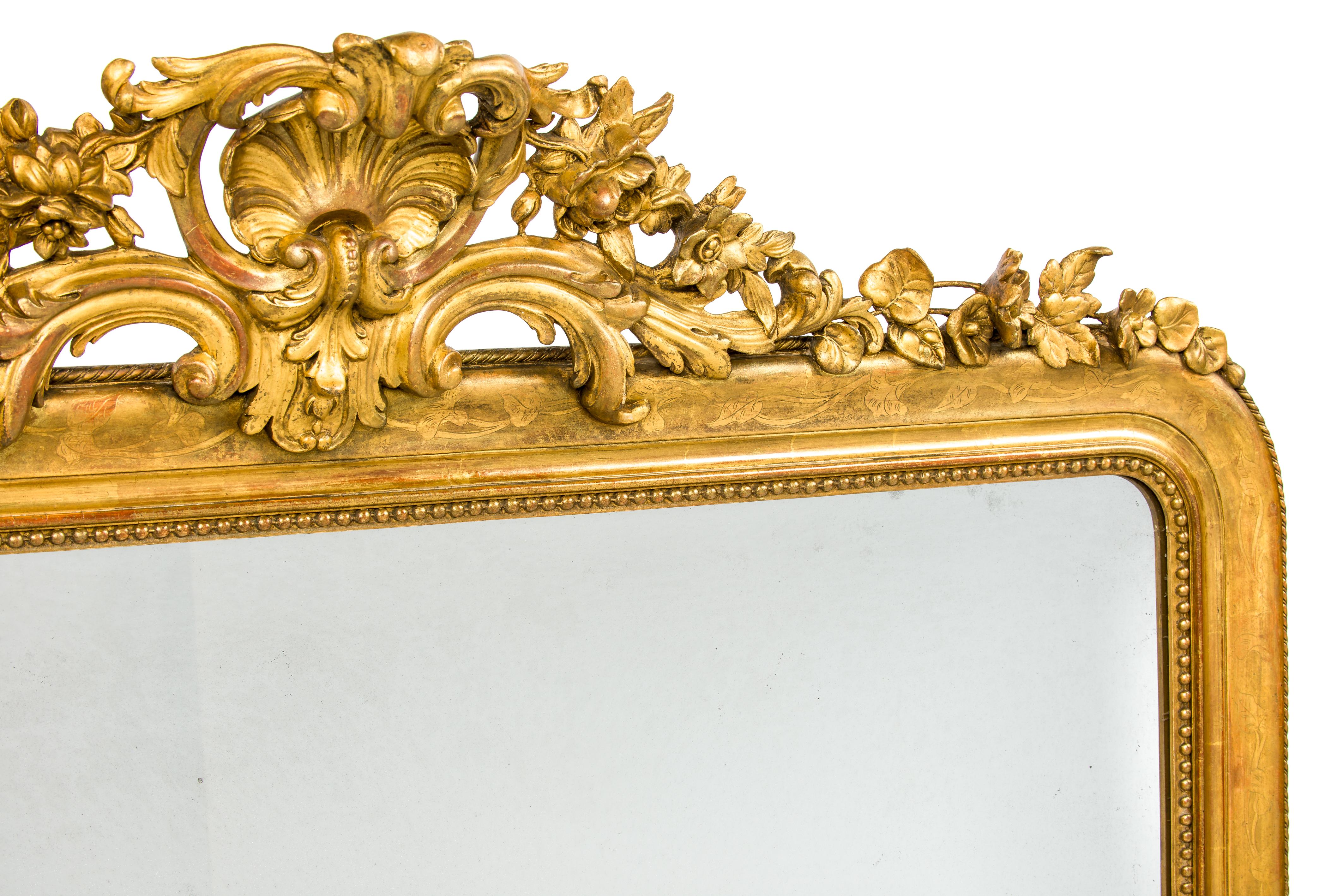 An impressive and unique gold leaf gilt mirror was made in France circa 1850. The mirror is horizontal oriented as opposed to the 99% of vertical oriented French mirrors. The mirror frame was decorated with an elaborate crest, depicting a central