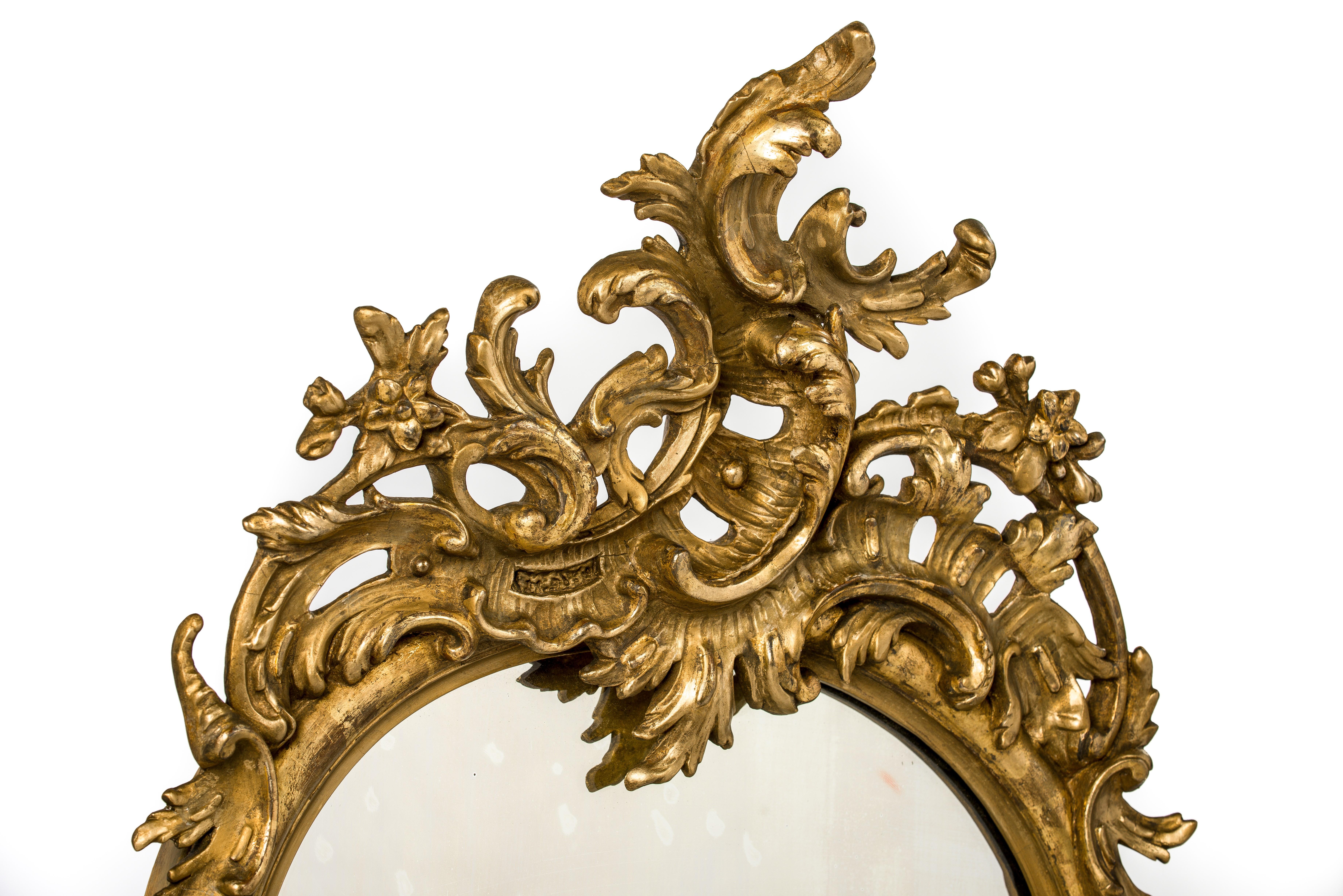 This beautiful abundant ornamented French mirror was made in the late 19th century. Its serpentine shape was made in solid pine smoothened with gesso. The frame is completely decorated with classic French ornaments such as C scrolls, flowers,