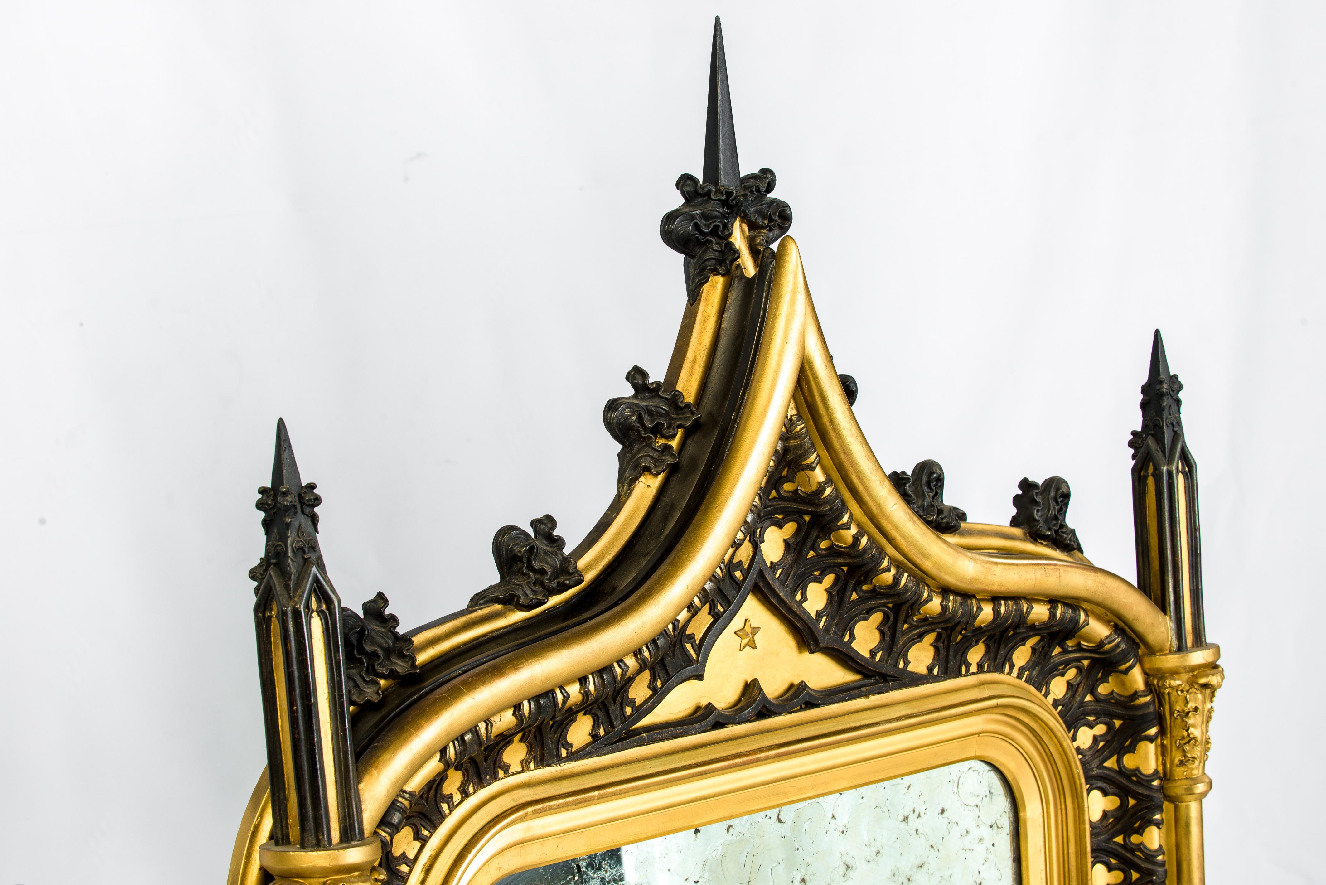 This bold antique French gothic mirror was made in France, circa 1840.
The giltwood frame is elaborately decorated with black tracery and spires that make a beautiful contrast with the gold. 
The arched top and its intricate decoration make this