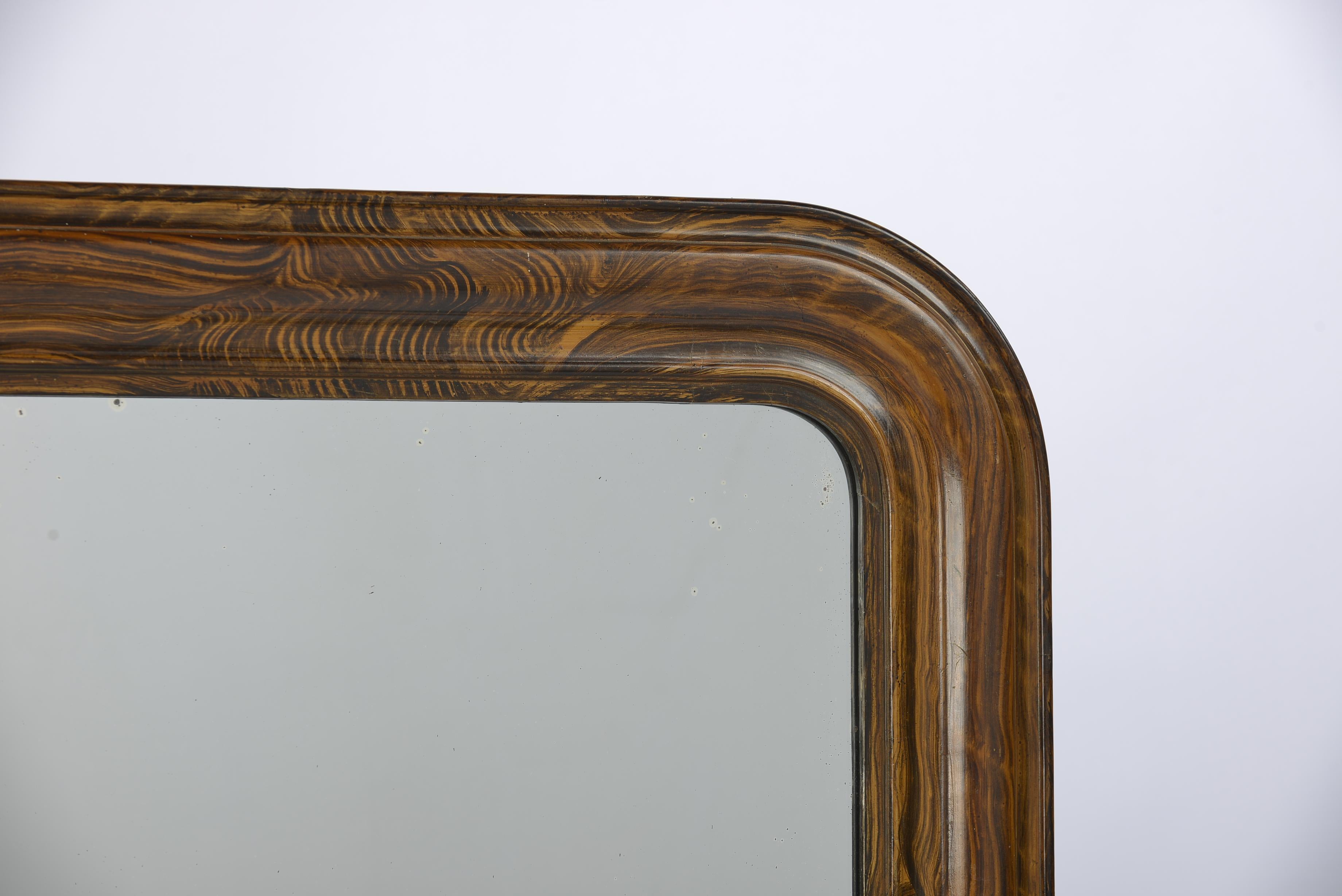 This Louis Philippe mirror was made in Northern France in the late 1800s.
The mirror has a solid pine frame that was smoothened with gesso. The mirror frame is painted to resemble rosewood with a beautiful grain pattern. The mirror has the original