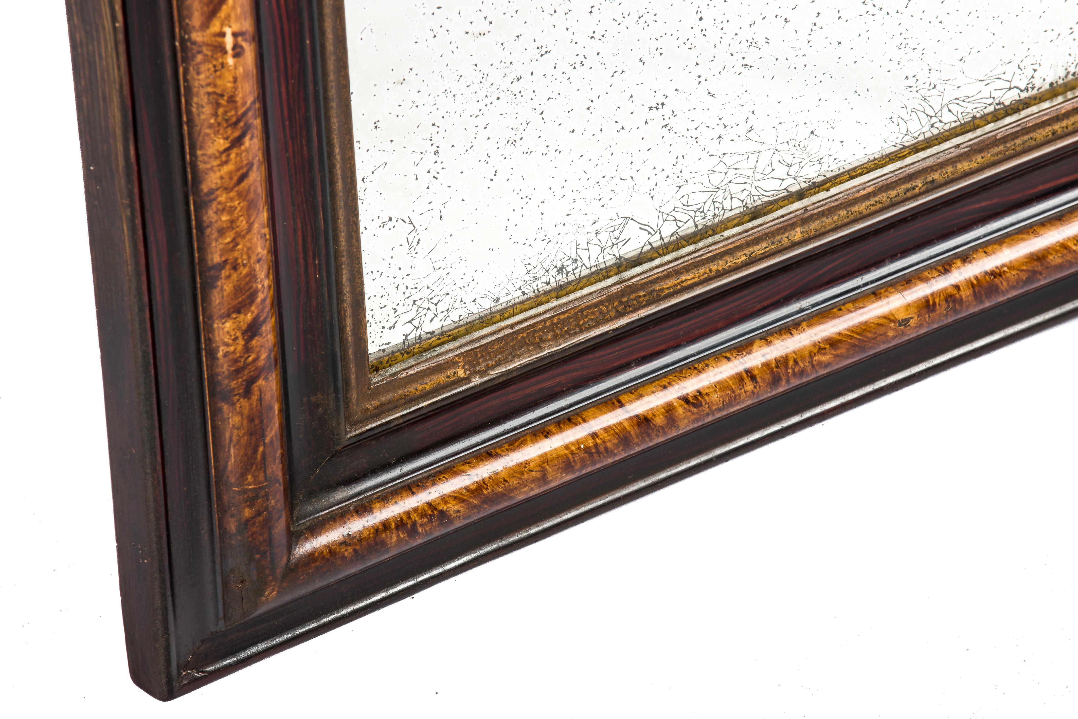 This Louis Philippe mirror was made in Northern France in the late 19th century, circa 1890. The mirror has a solid pine frame that was smoothened with gesso. The mirror frame is painted to resemble rosewood with a beautiful grain pattern. The most