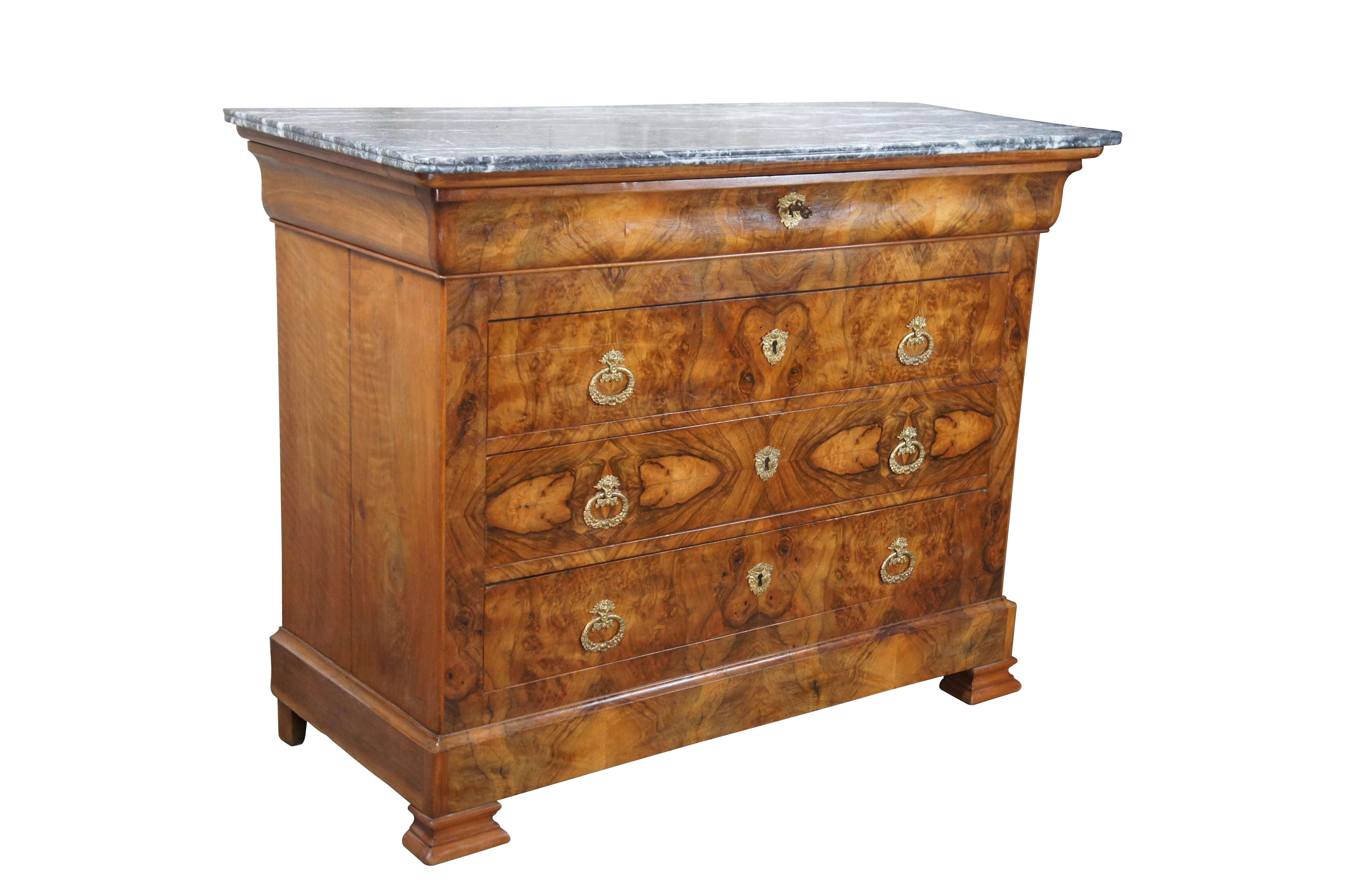 A Louis Philippe Walnut Commode, c. 1840.  Features a rectangular form made from walnut with matchbook veneer burled drawer fronts and Saint Anne Des Pyrenees Marble top.  Features an ogee-molded frieze drawer over three drawers with ornate gilt